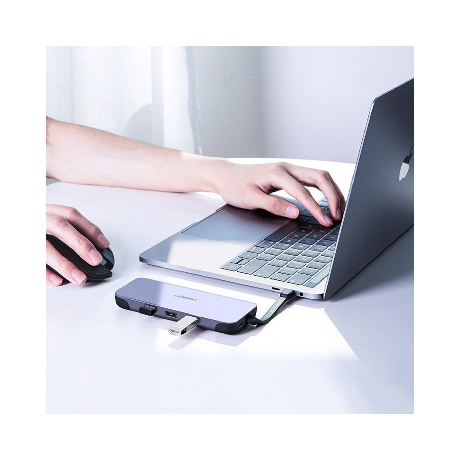 Person benutzt einen Laptop, der mit einem Hub und einer Maus verbunden ist.