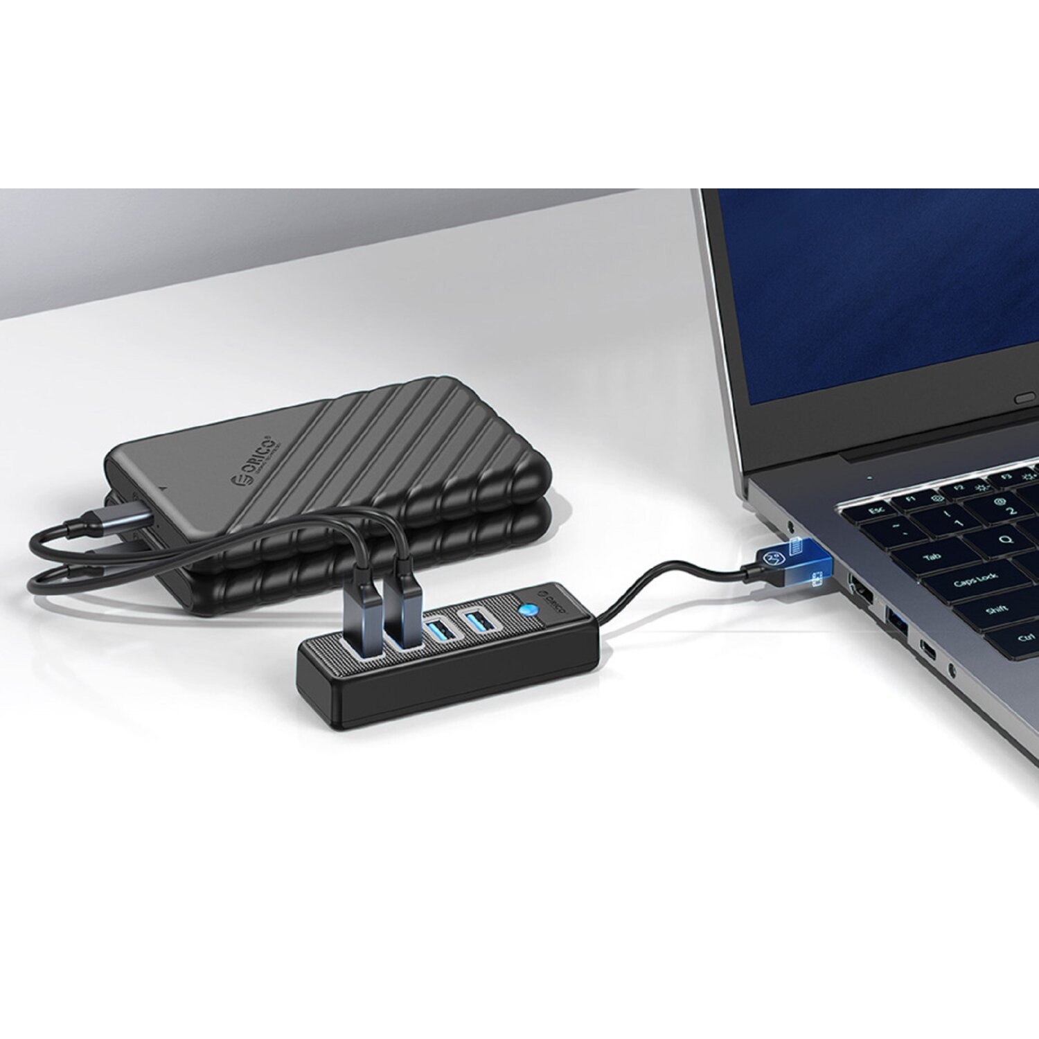 Ein schwarzer USB-Hub ist mit einem Laptop und einer Powerbank verbunden.