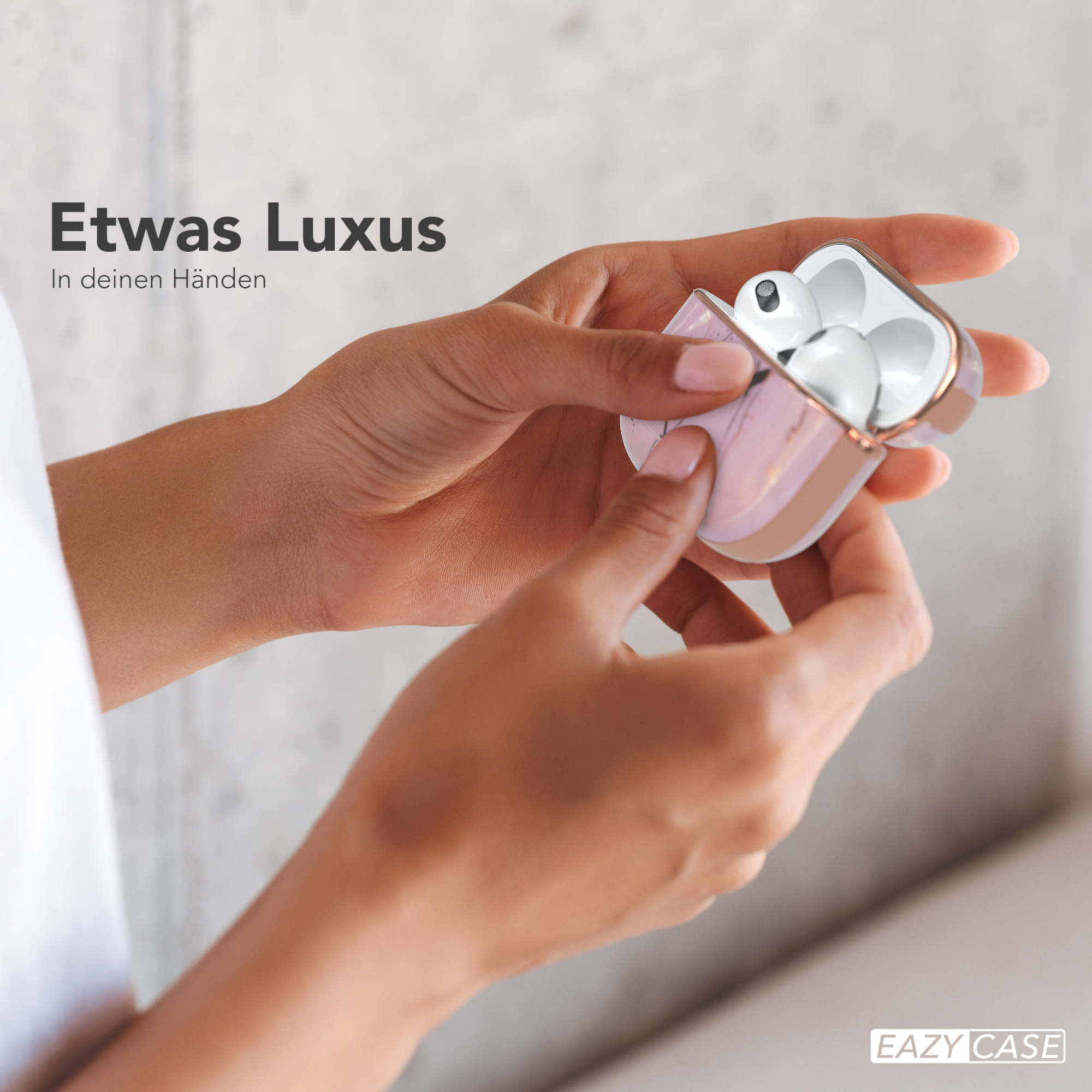 Hände halten eine pinkfarbene und goldene Ohrhörer-Hülle. Text: 'Etwas Luxus In deinen Händen'.