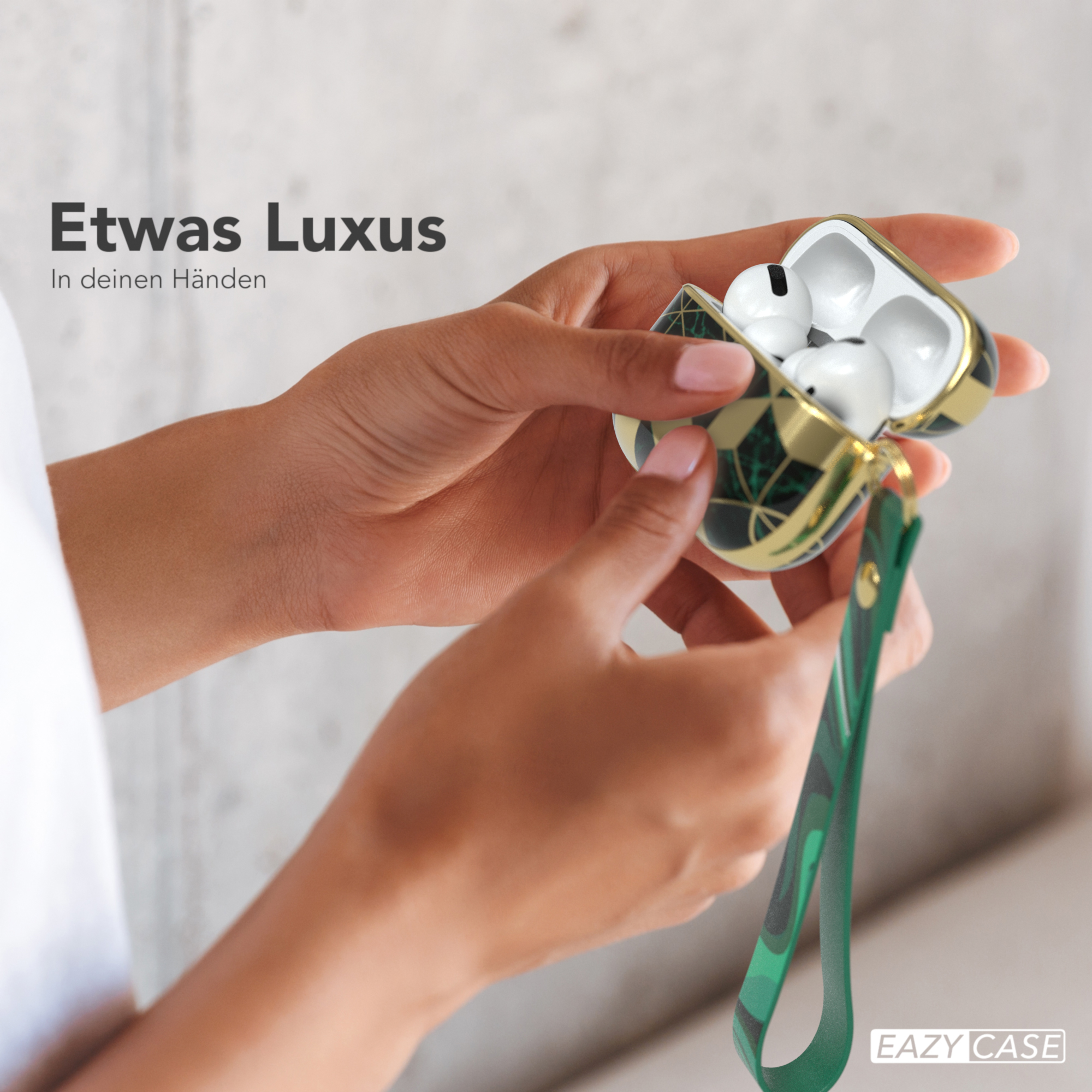 Hände einer Frau halten offenes AirPods-Case. Grün-Gold-Design, weiße Ohrhörer, weicher Fokus.