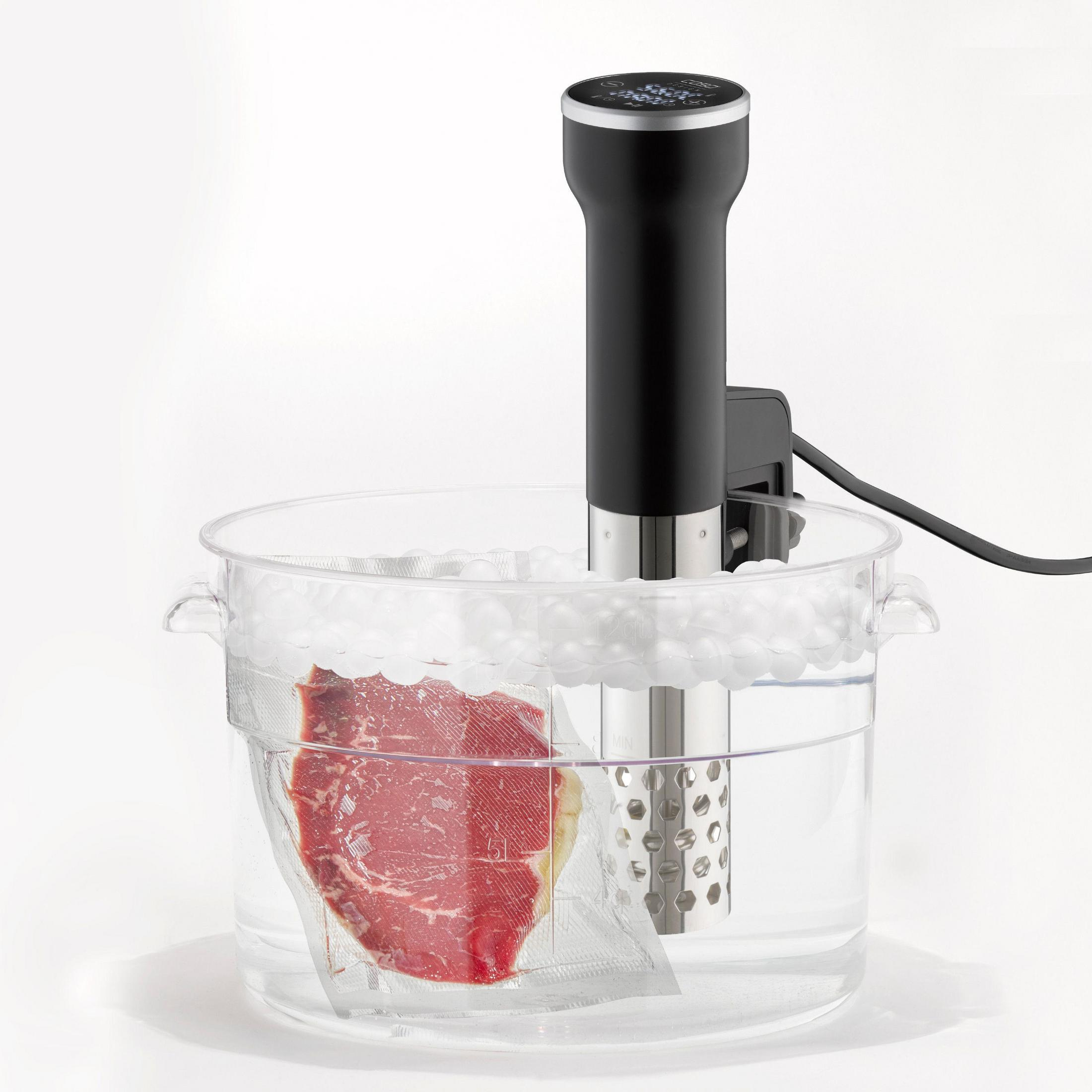 Sous-Vide-Maschine mit Steak im Beutel. Die Maschine befindet sich in einem transparenten Behälter mit Wasser.