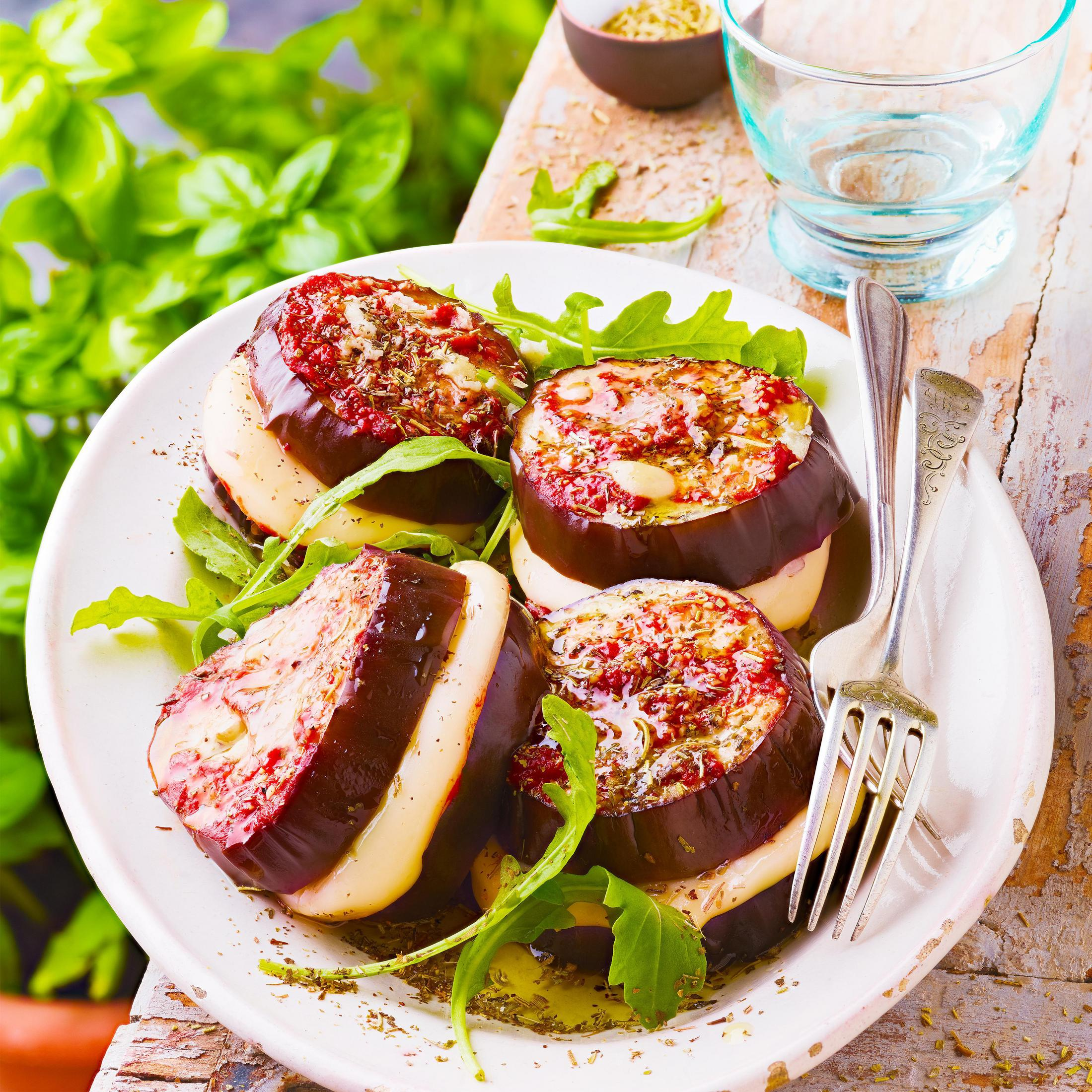 Teller mit Auberginenröllchen mit Käse und Tomate, garniert mit Rucola.