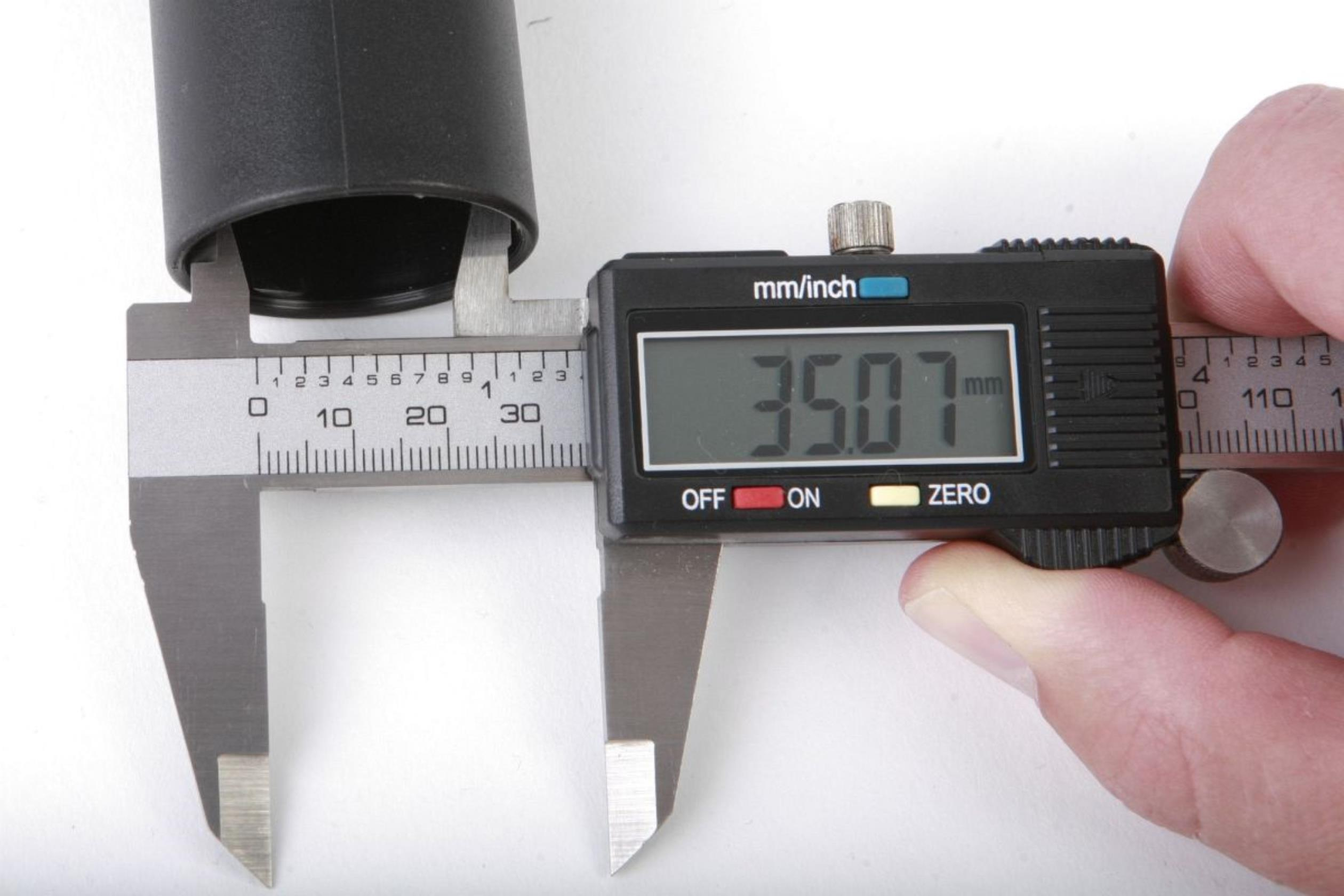 Digitale Messschieber messen den Durchmesser eines schwarzen zylindrischen Objekts. Anzeige: 35,07 mm.