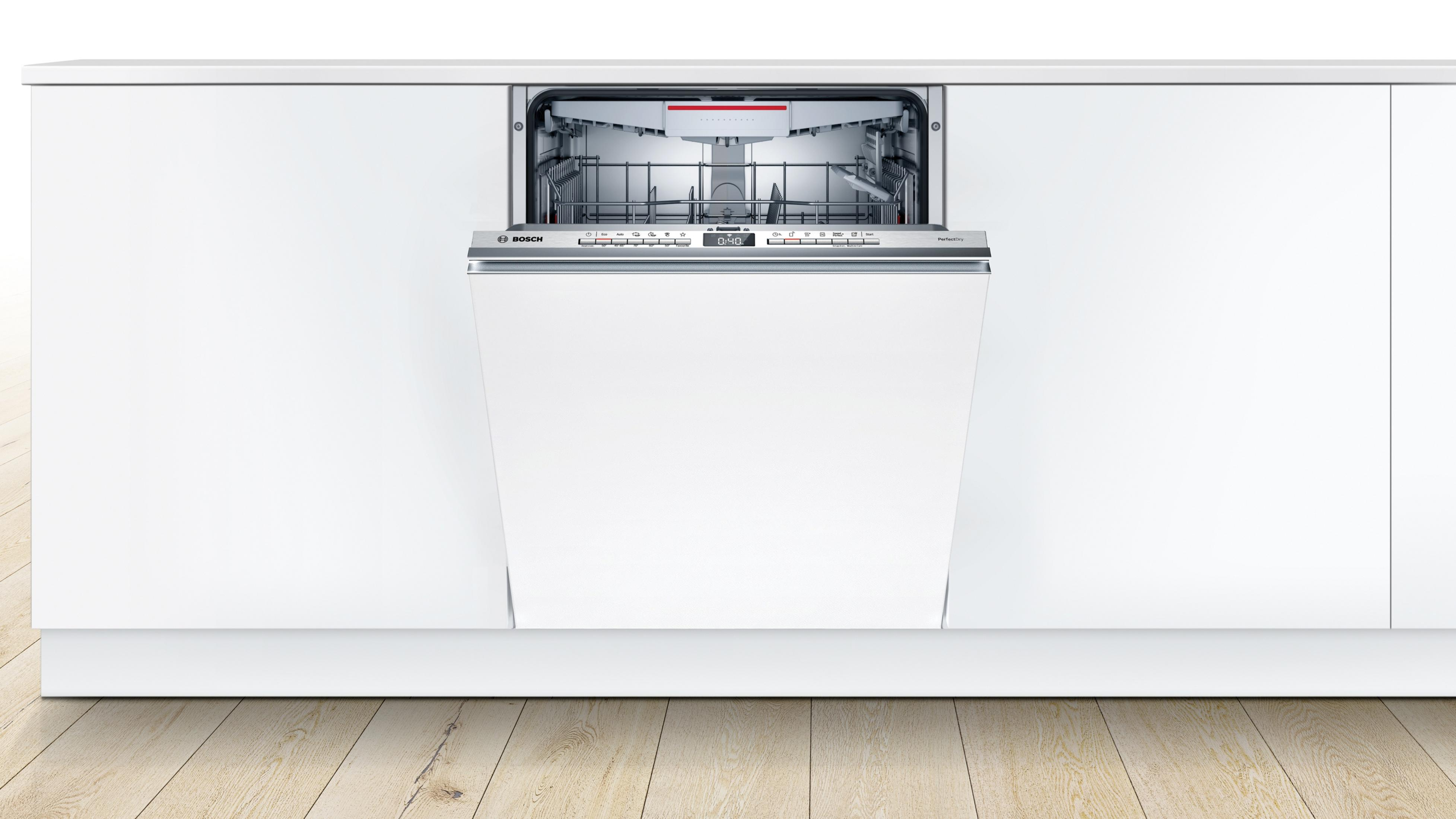 Un lavavajillas blanco empotrado en un armario de cocina blanco, con la puerta abierta.