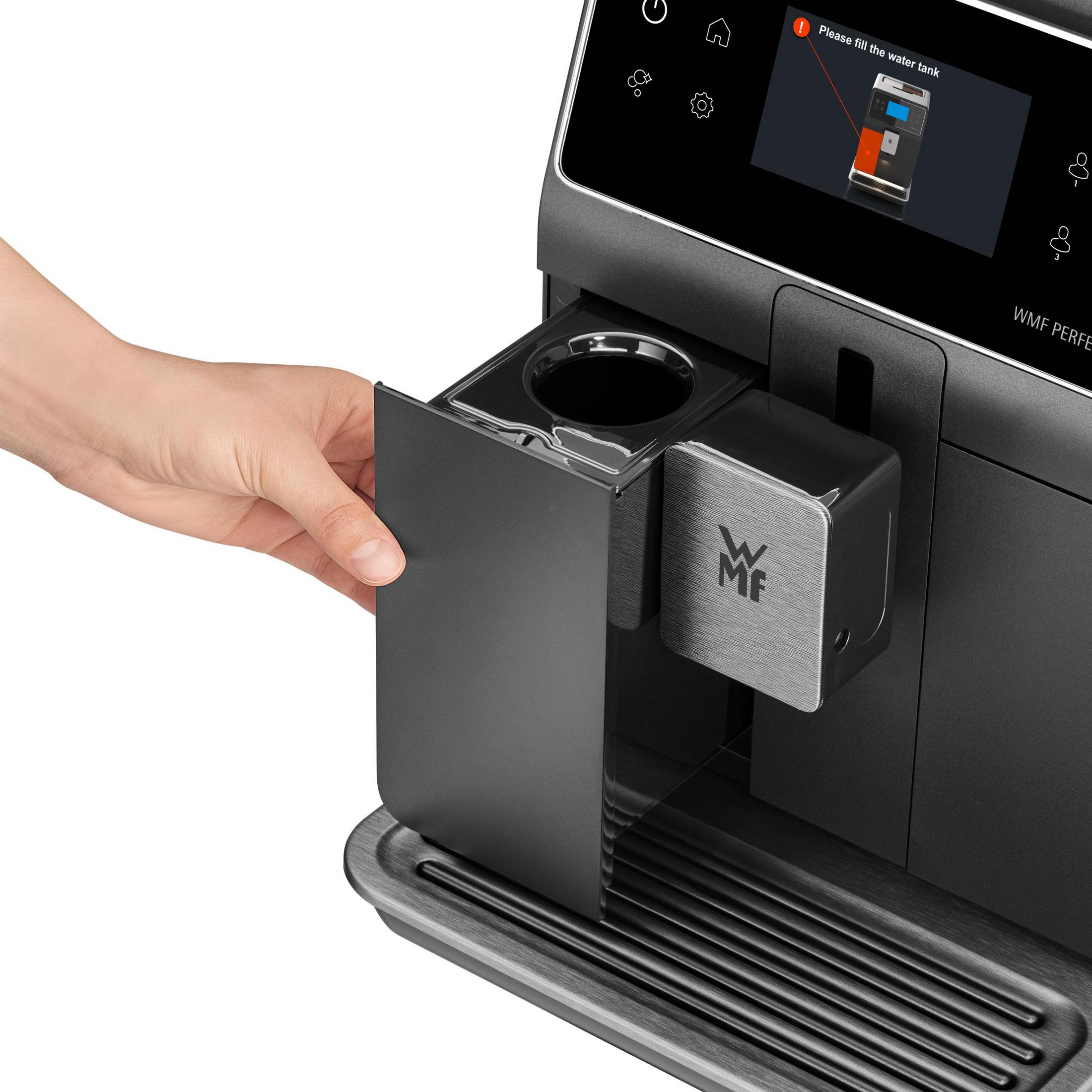 Nahaufnahme einer WMF Kaffeemaschine. Eine Hand öffnet den Behälter. Der Bildschirm zeigt 'Bitte Wassertank füllen'.
