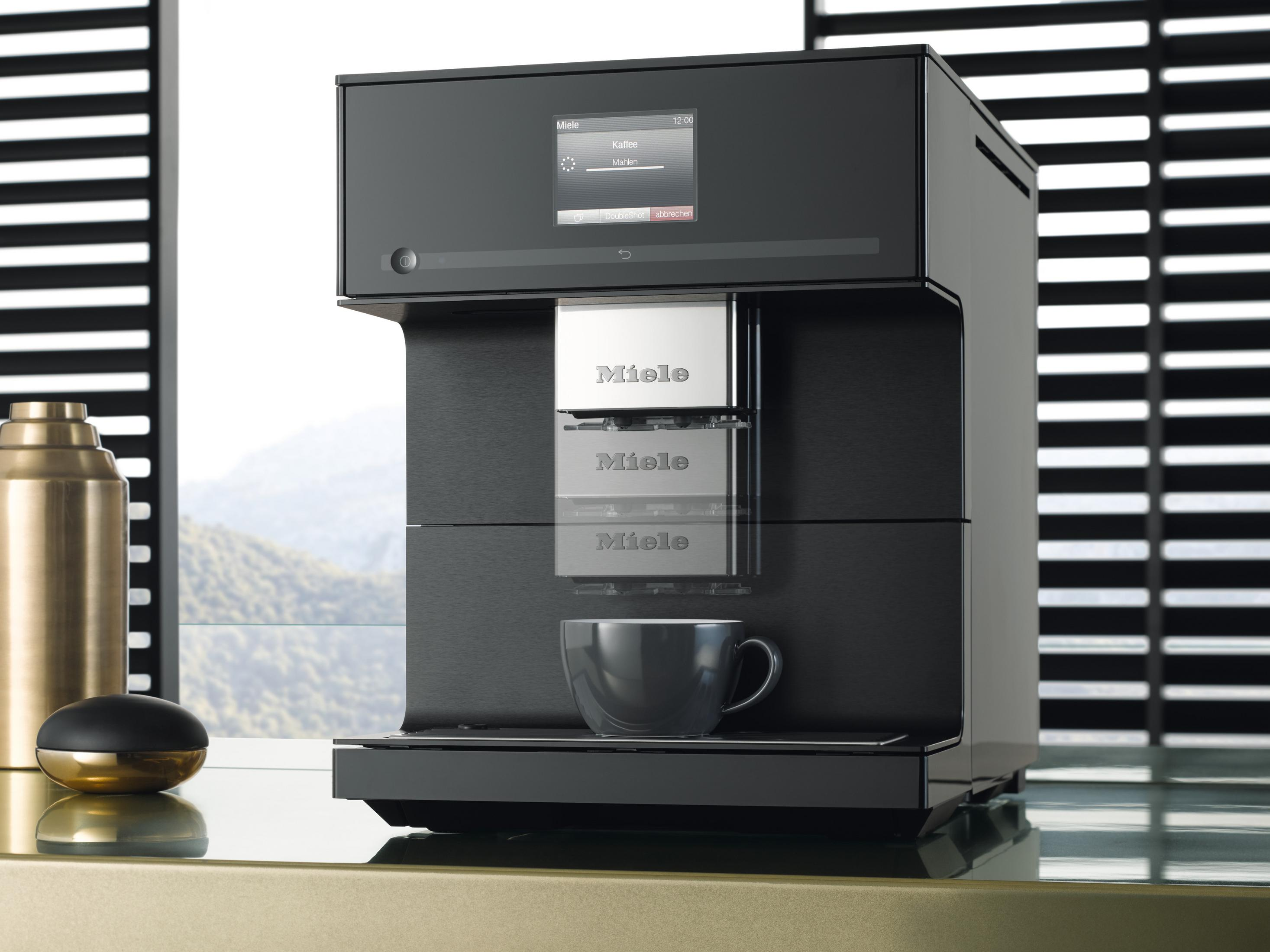 Schwarze Miele Kaffeemaschine. Kaffeetasse auf dem Tablett. Display zeigt Kaffeeoptionen.
