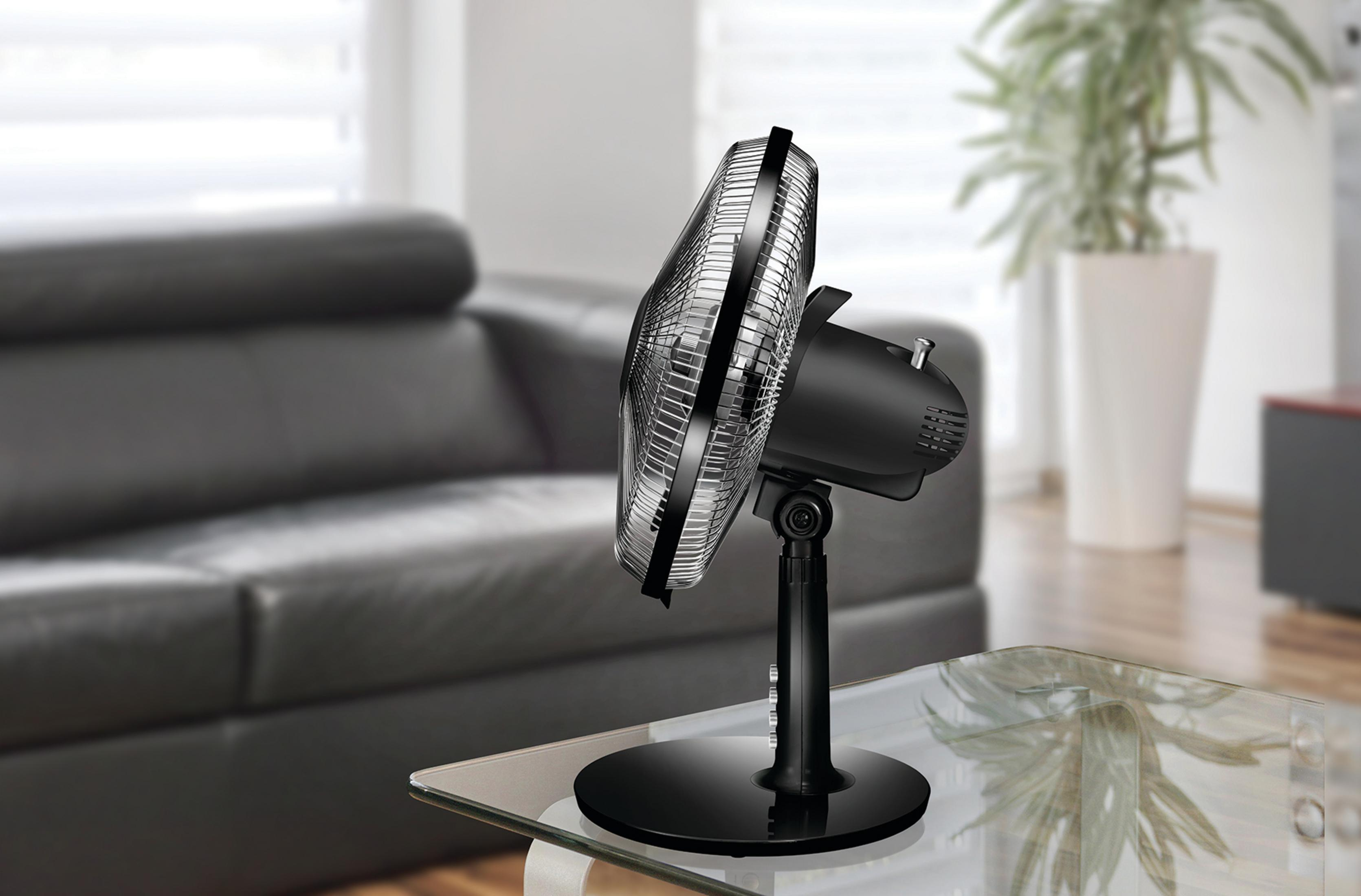 Schwarzer Ventilator auf einem Tisch. Tisch mit Glasplatte, verschwommener Hintergrund des Raumes.