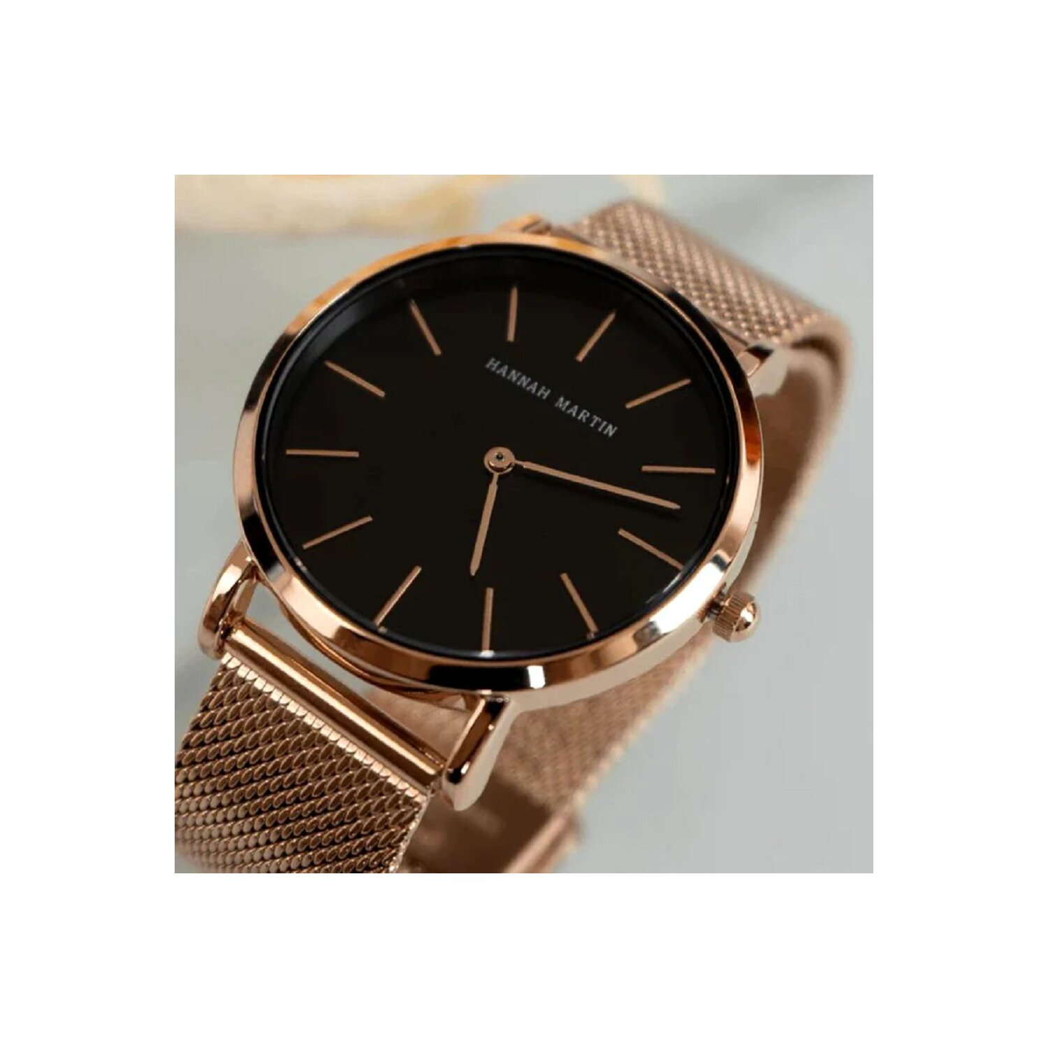Eine Uhr mit schwarzem Zifferblatt und roségoldfarbenem Armband. Auf dem Zifferblatt steht Hannah Martin.