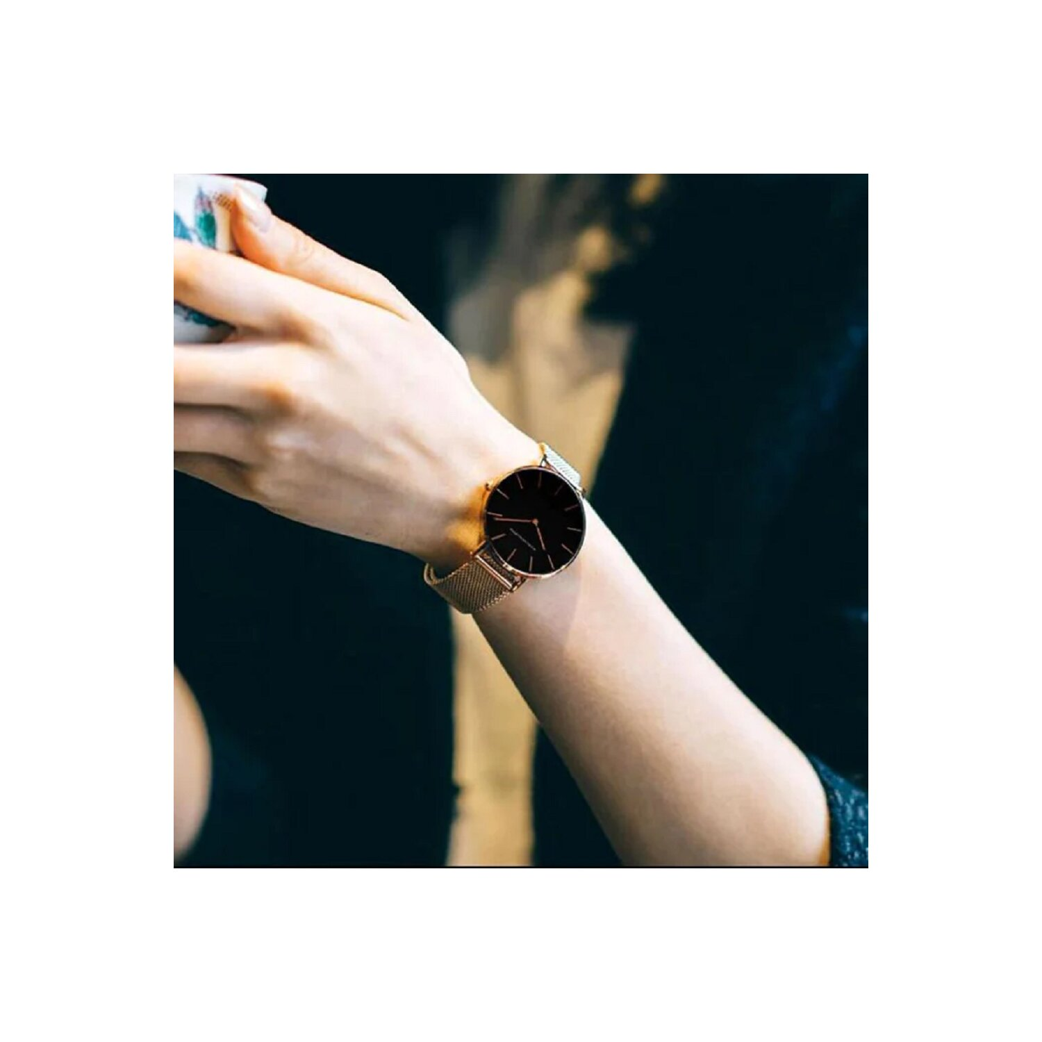 Handgelenk einer Person mit einer roségoldenen Uhr und einem metallischen Mesh-Armband.