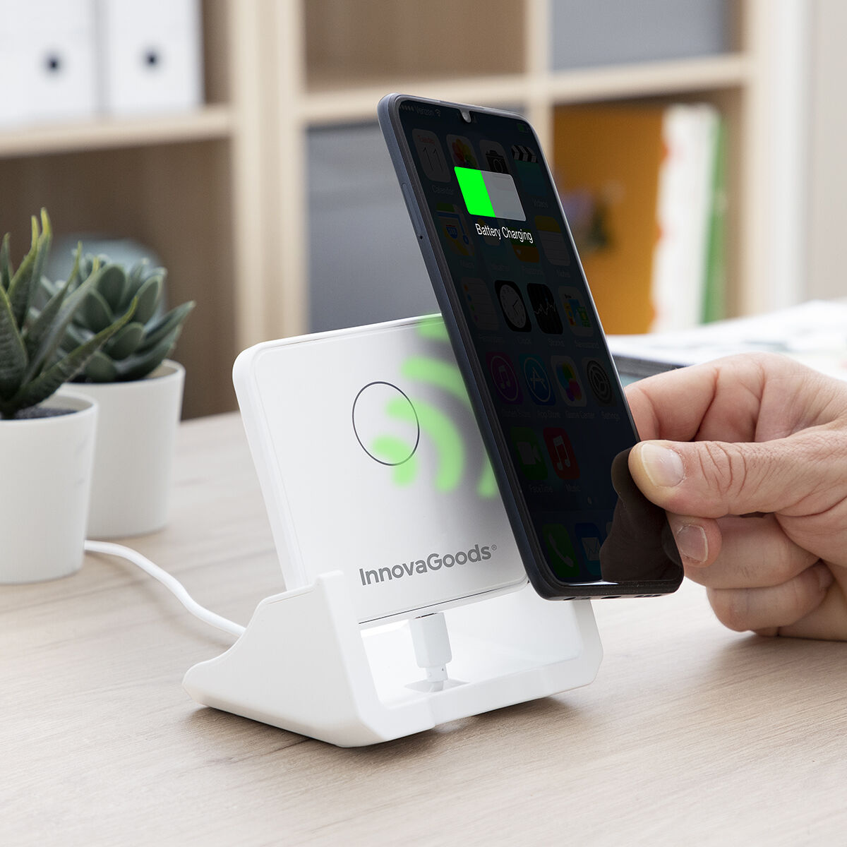 Ein weißes kabelloses Ladegerät lädt ein schwarzes Smartphone auf. Das Telefon zeigt ein Ladesymbol an.