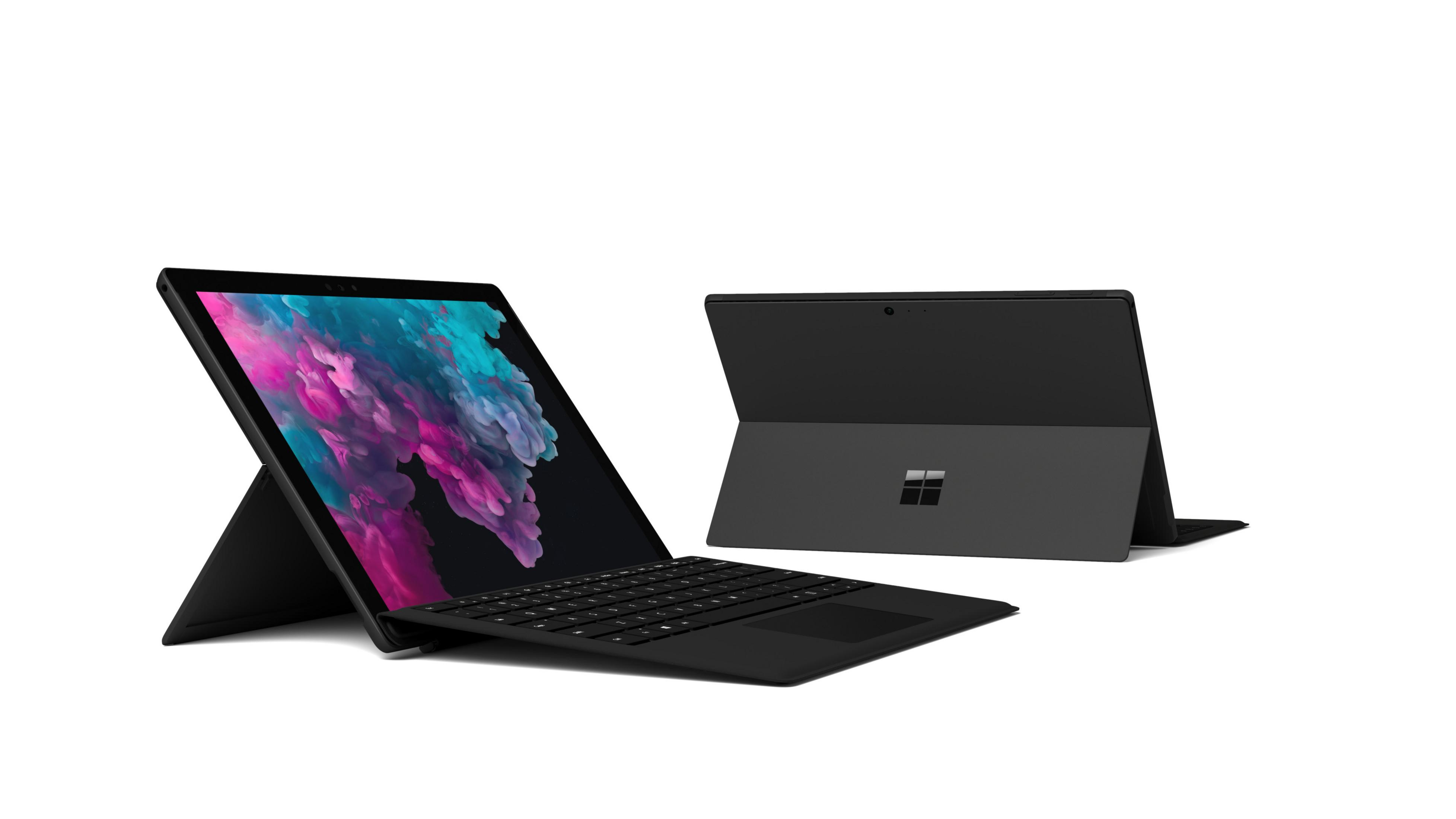 Zwei schwarze Microsoft Surface Laptops, einer offen und einer geschlossen, auf weißem Hintergrund.