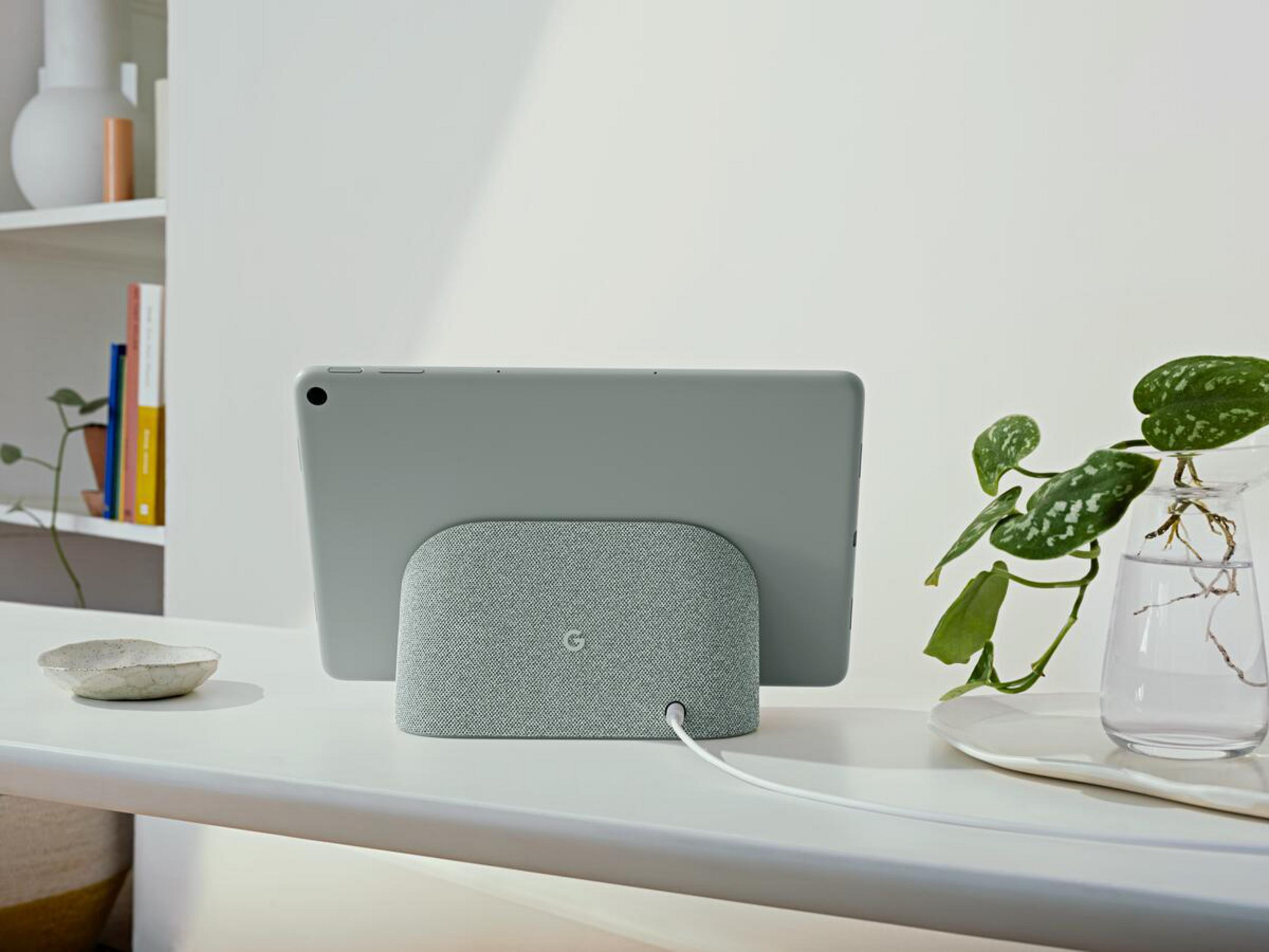 Ein graues Tablet auf einer weißen Oberfläche mit einem grauen Lautsprecherdock.