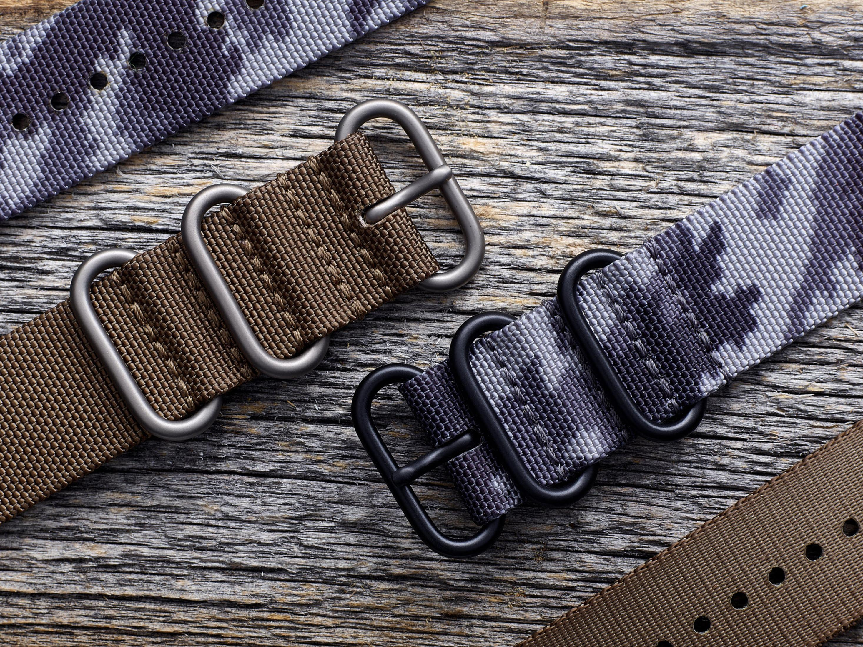 Zbliżenie pasków do zegarków z metalowymi klamrami. Pokazano różne kolory i wzory.