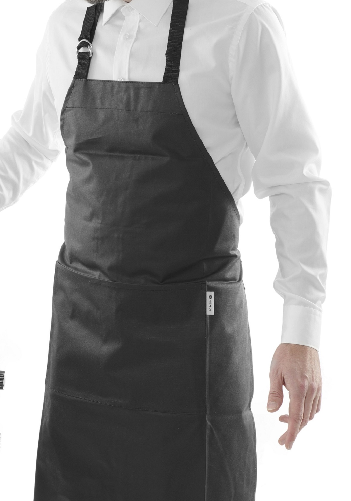 Una persona indossa un grembiule nero. Il grembiule ha tasche. Sotto una camicia bianca.