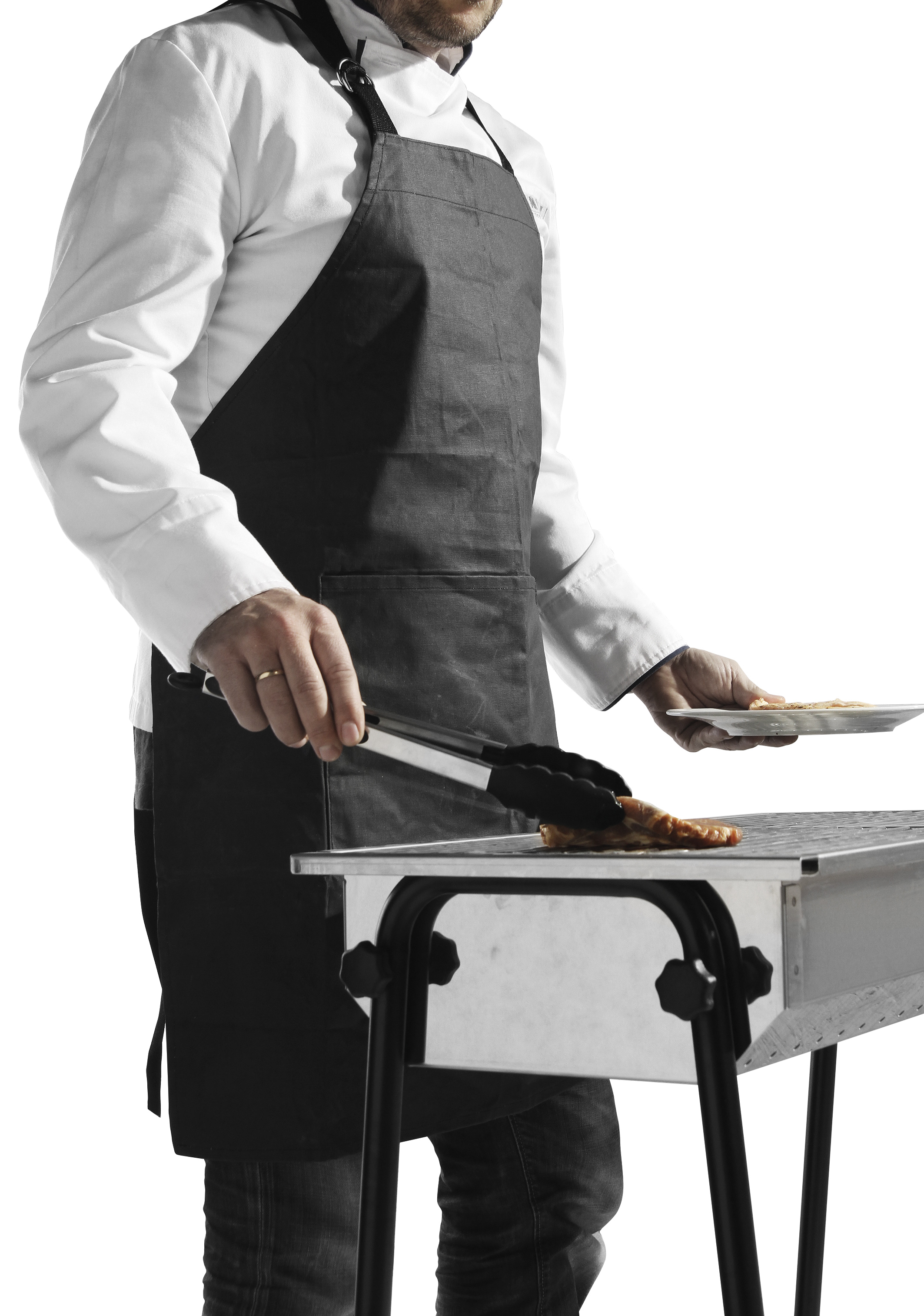 Uno chef con grembiule che griglia cibo. Usa le pinze per girare il cibo su una piccola griglia.