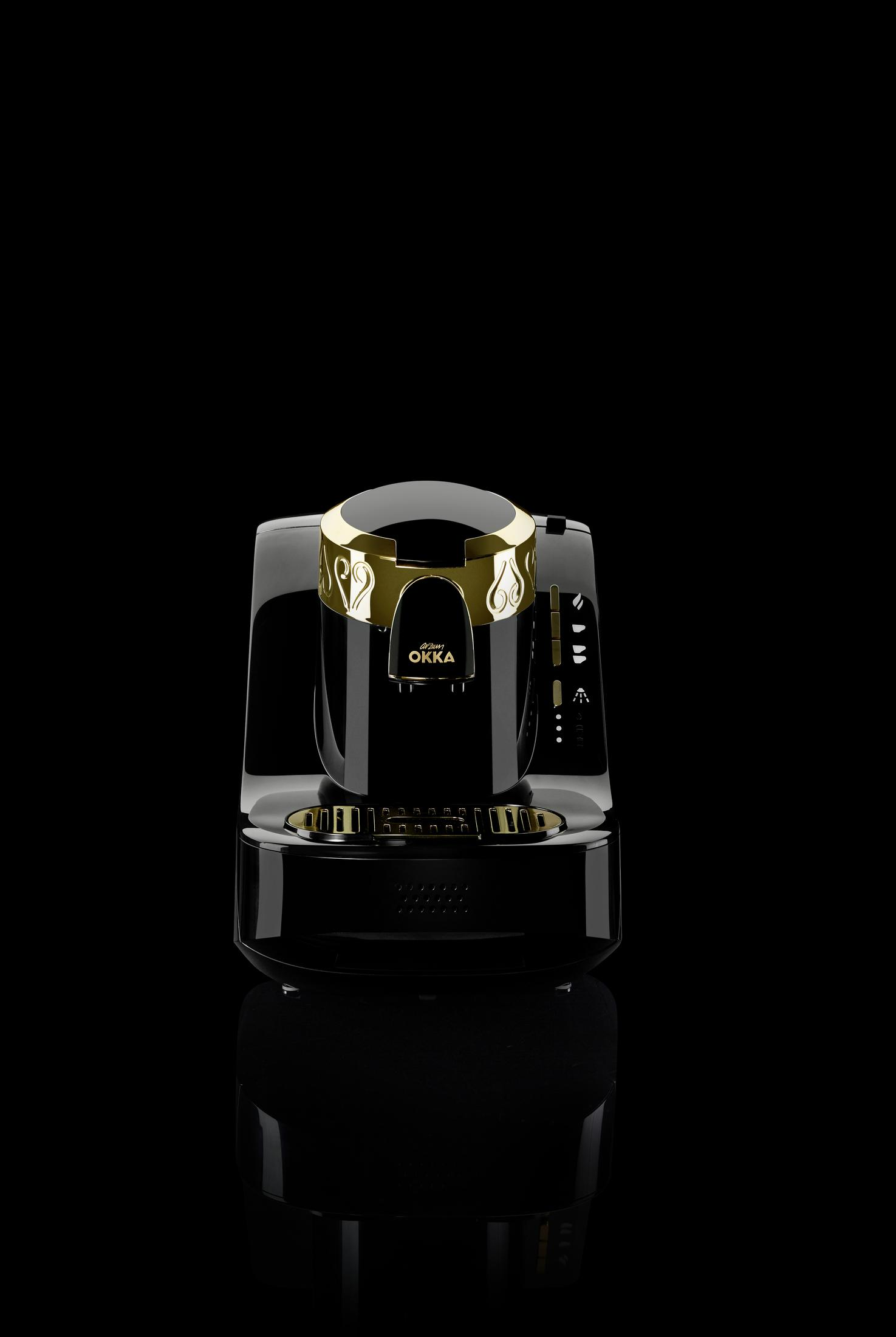 Macchina da caffè nera con dettagli dorati. Ha un design elegante. Sfondo nero.