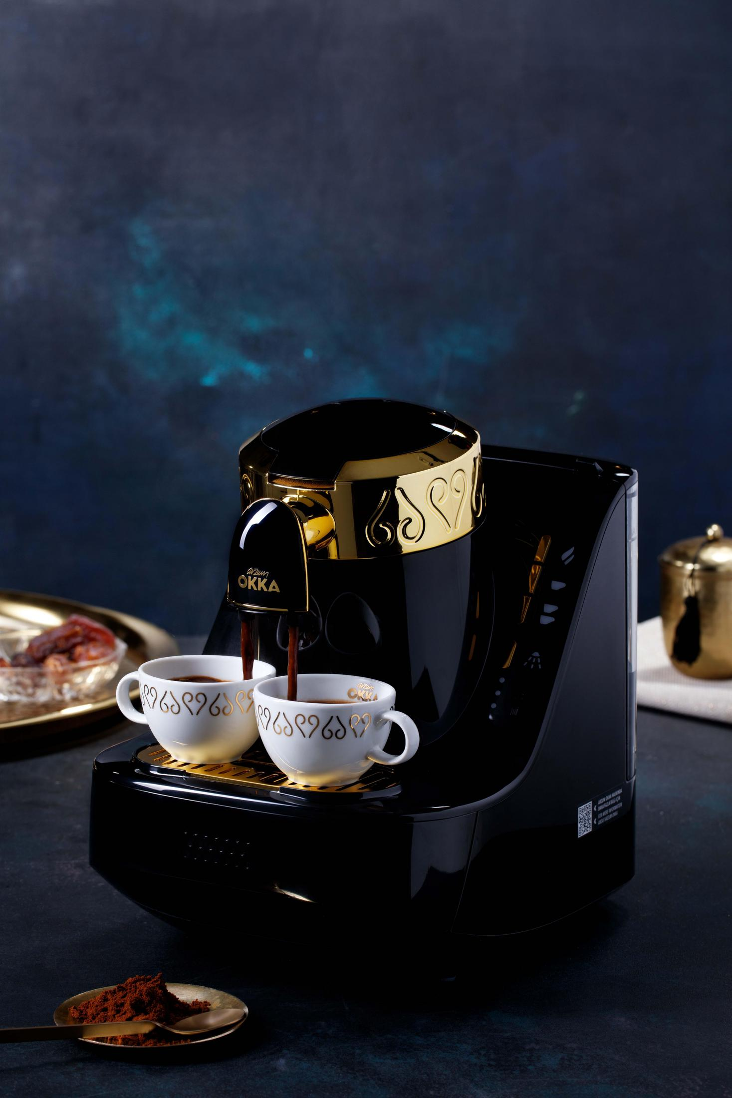 Macchina del caffè che eroga caffè in due tazze bianche. Polvere marrone in un cucchiaio d'oro vicino.
