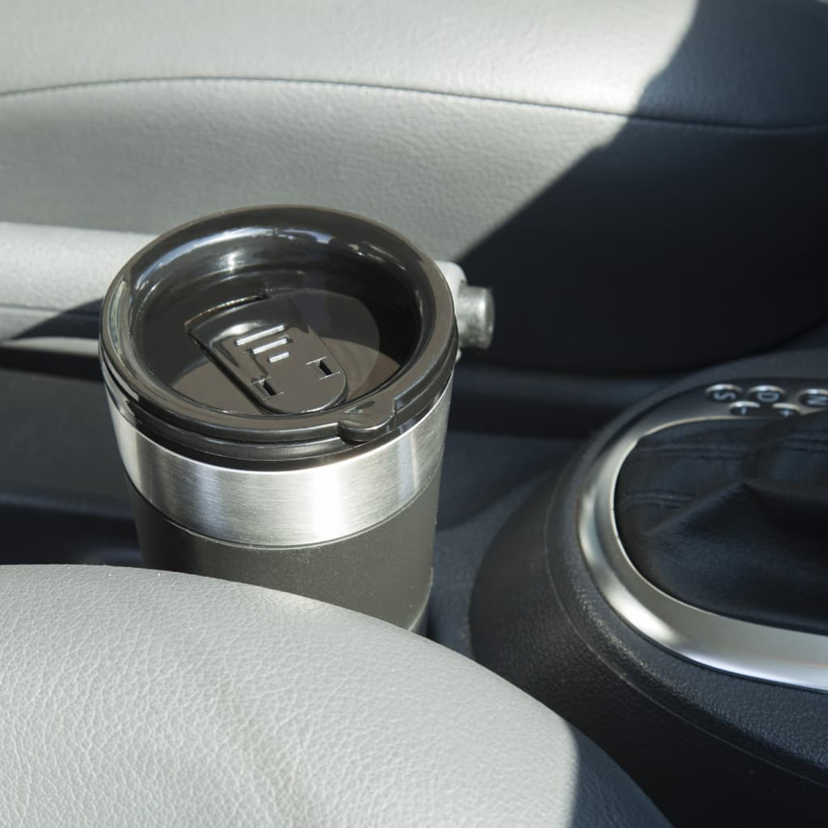 Uchwyt na kubek samochodowy z czarno-srebrnym kubkiem w szarym wnętrzu.