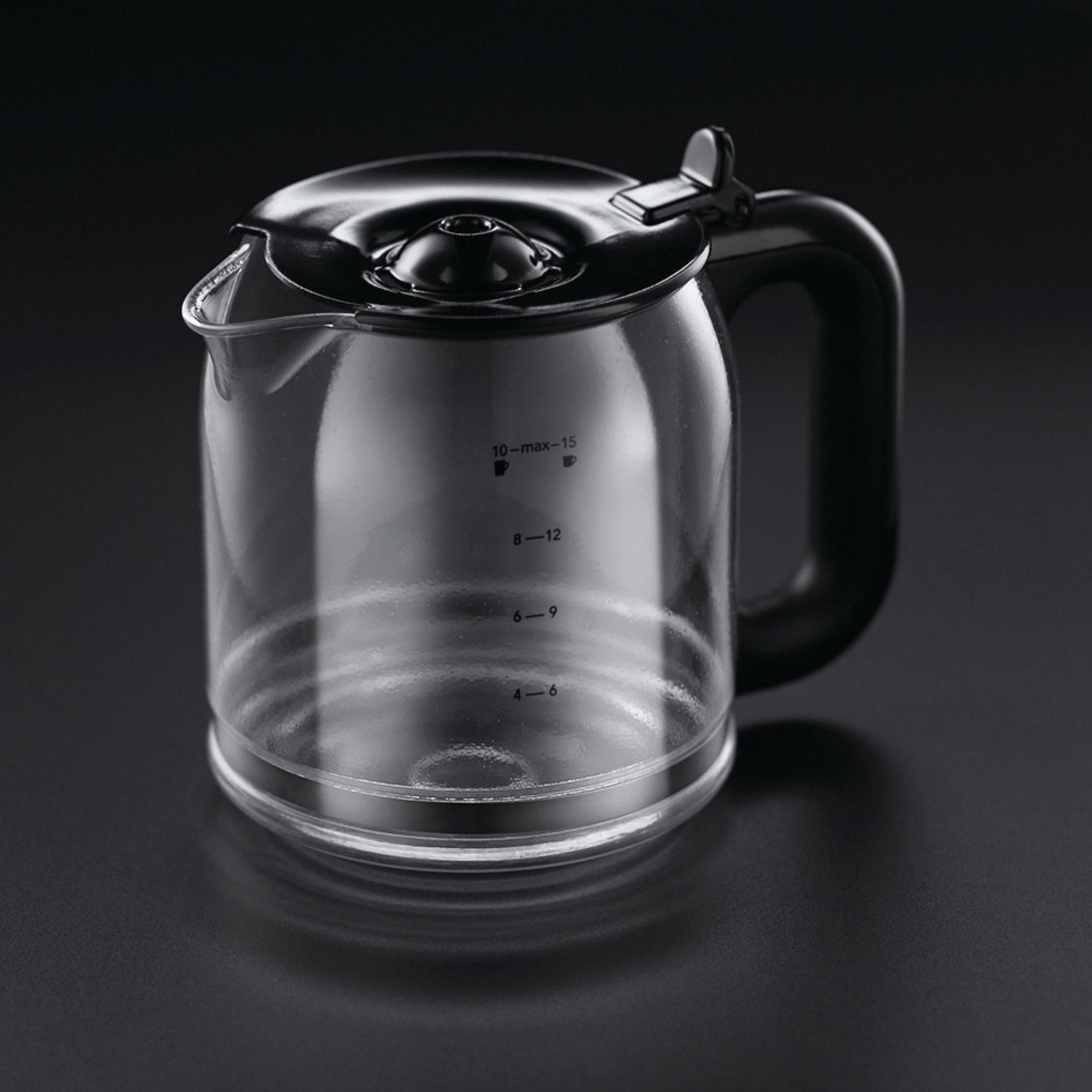 Jarra de café de vidrio con tapa y asa negras sobre fondo negro.