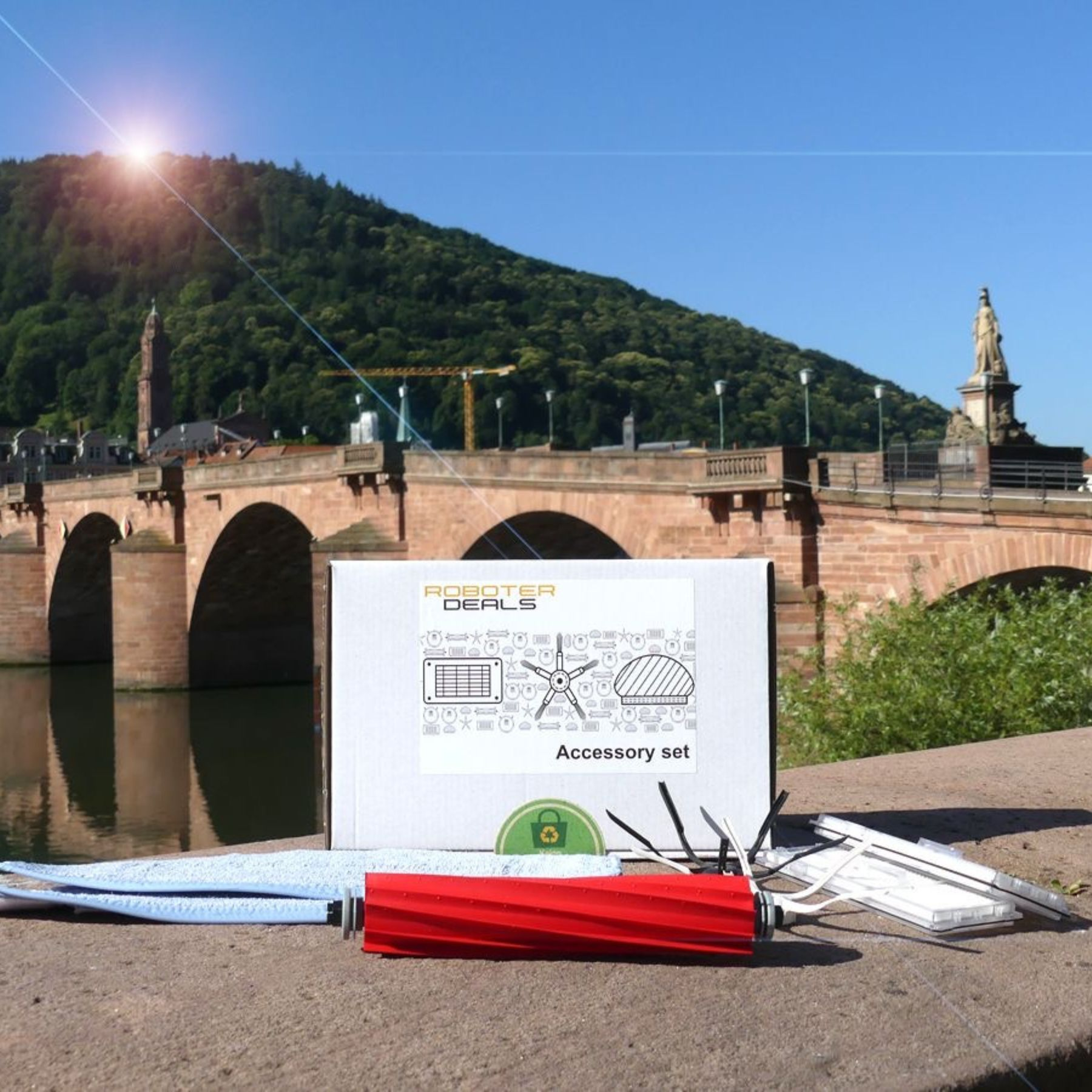 Roboter Deals Zubehörset auf Betonoberfläche mit Brücke und Fluss im Hintergrund.