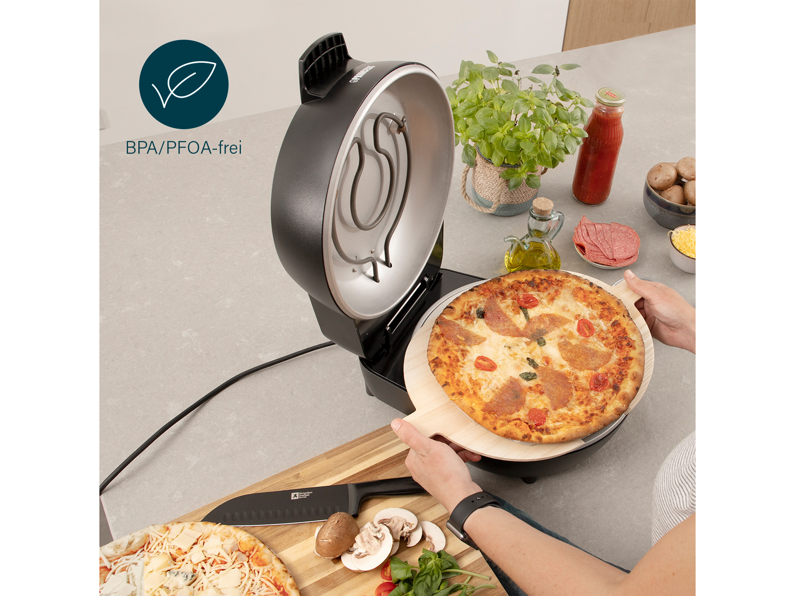 Pizza siendo retirada de un horno de pizza con una pala de madera. Ingredientes en la encimera.