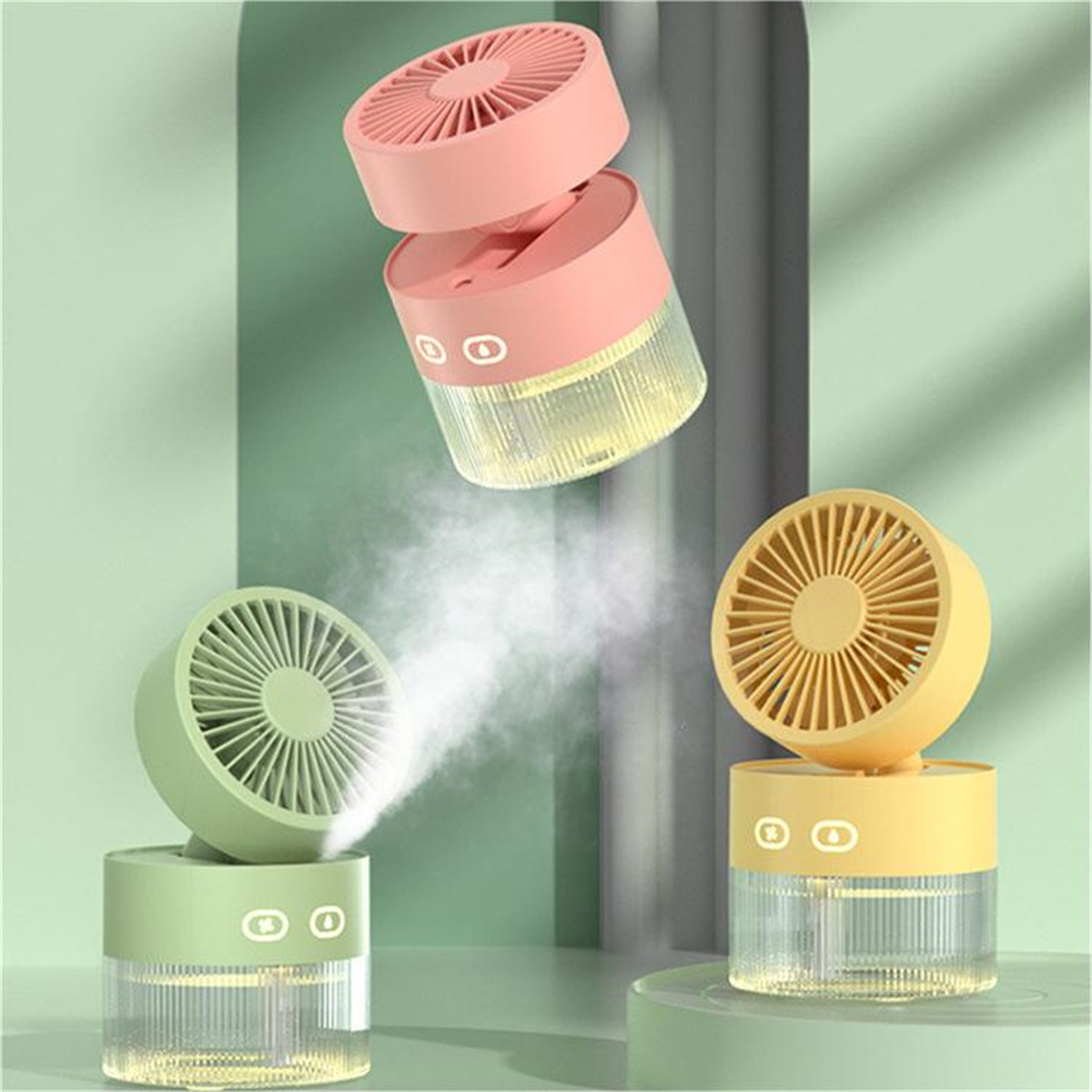 Drei kleine, bunte Ventilatoren. Zwei sind rosa und grün, einer gelb. Sie haben einen Wassertank.