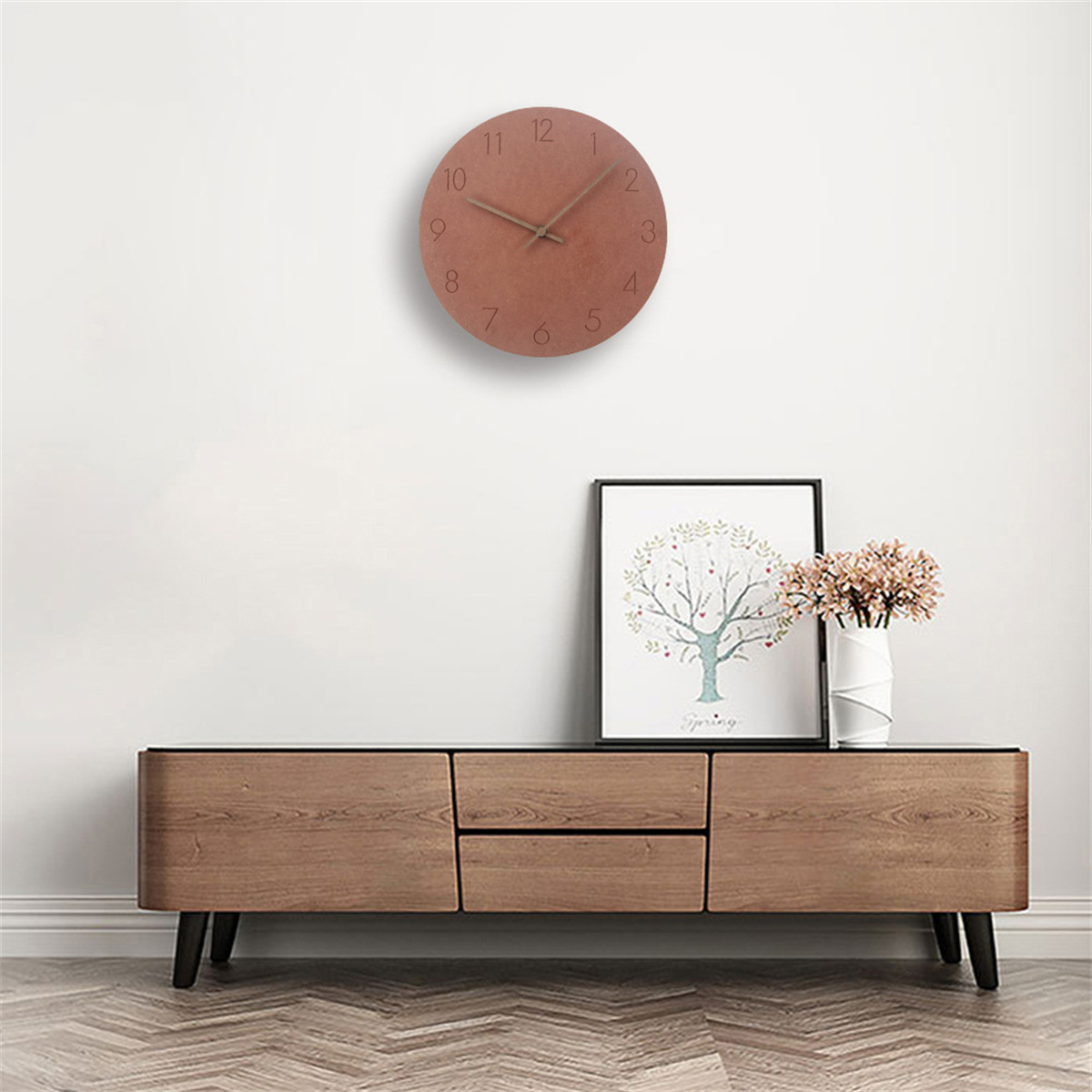 Eine Uhr an einer weißen Wand. Darunter ein Holzschrank mit Dekoration.