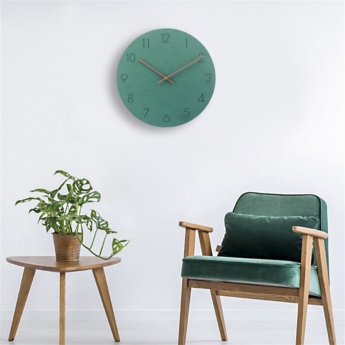 Eine grüne Wanduhr an einer weißen Wand, mit einem grünen Sessel und einem kleinen Tisch mit Pflanze.