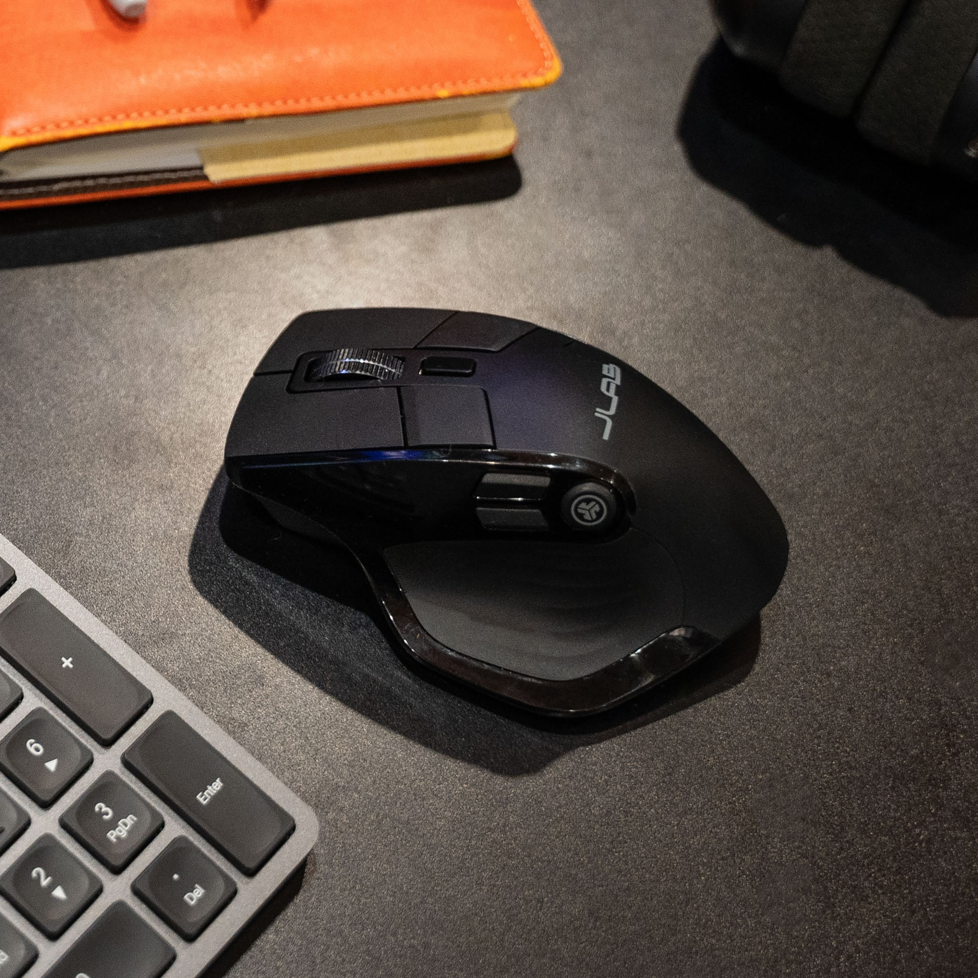Schwarze ergonomische Maus auf dunkler Oberfläche. Tastatur sichtbar.
