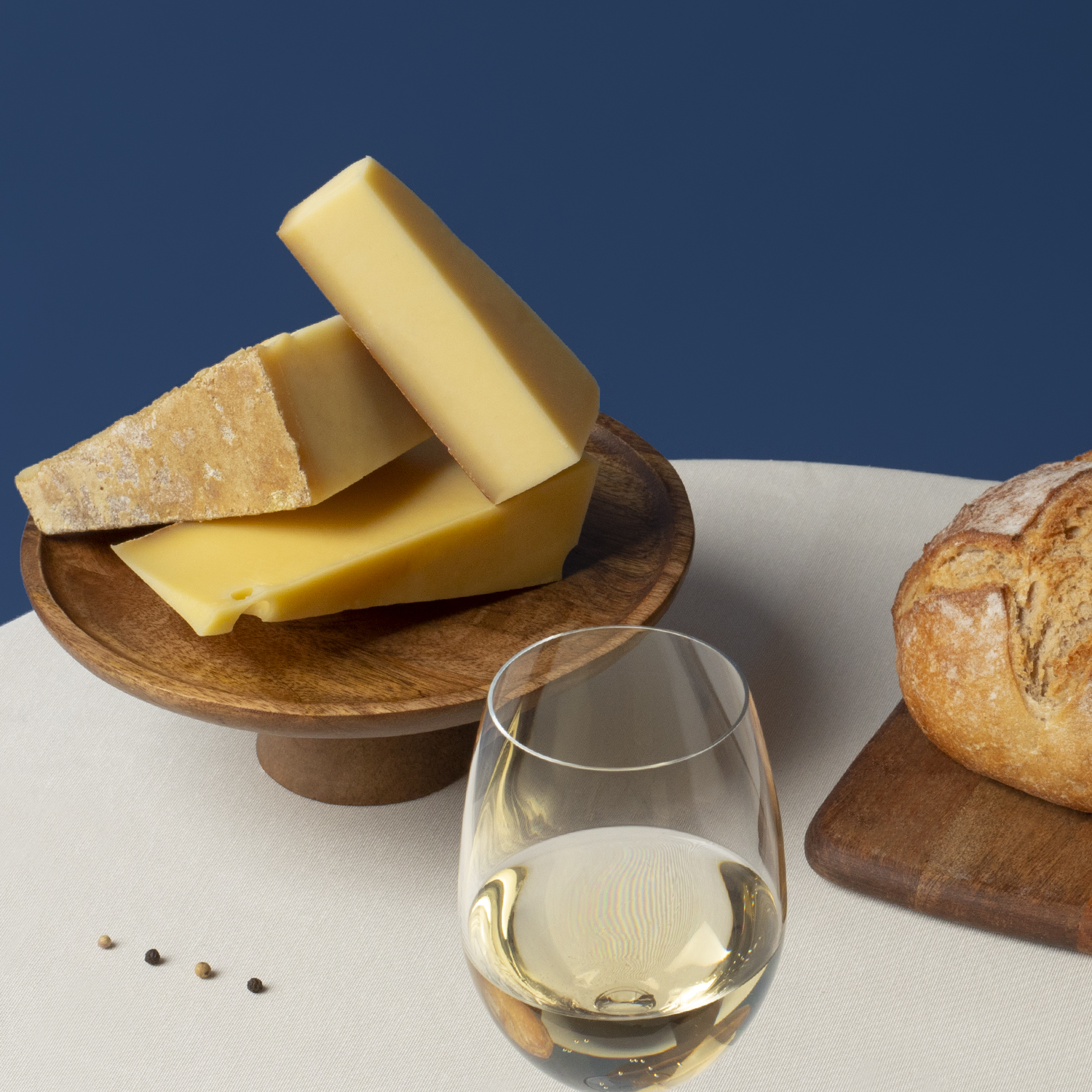 Käseplatte mit Brot und Wein. Käse auf Holzständer, Weißwein im Glas.