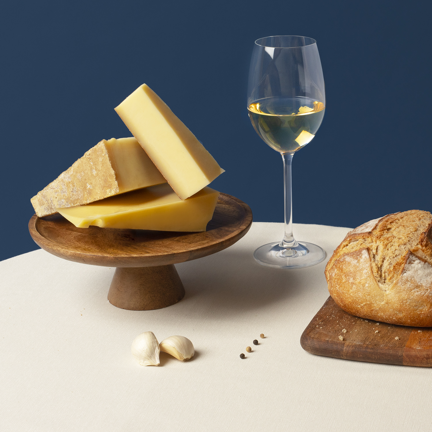 Piatto di formaggi con pane, aglio e vino. Formaggio su supporto in legno, vino bianco in un bicchiere.