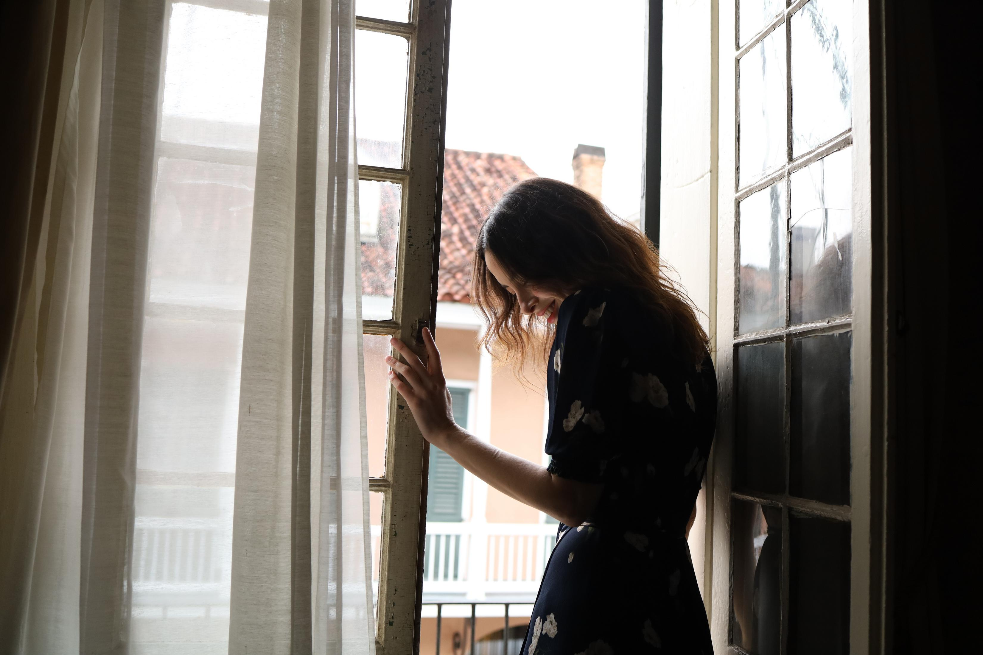 Femme près d'une fenêtre regardant dehors.