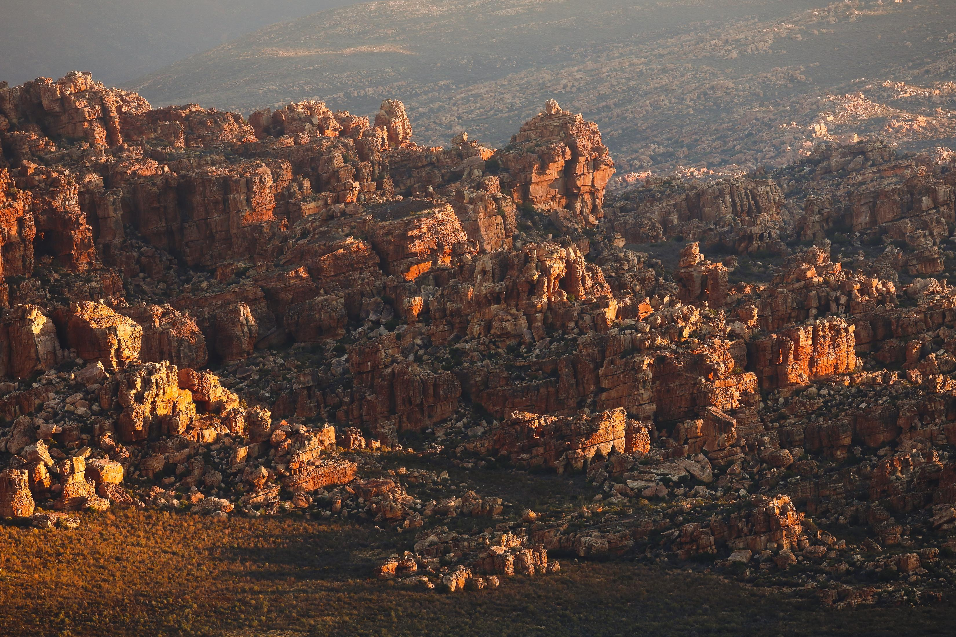 Skalisty krajobraz z czerwono-brązowymi skałami w świetle słonecznym. Tło jest rozmyte.