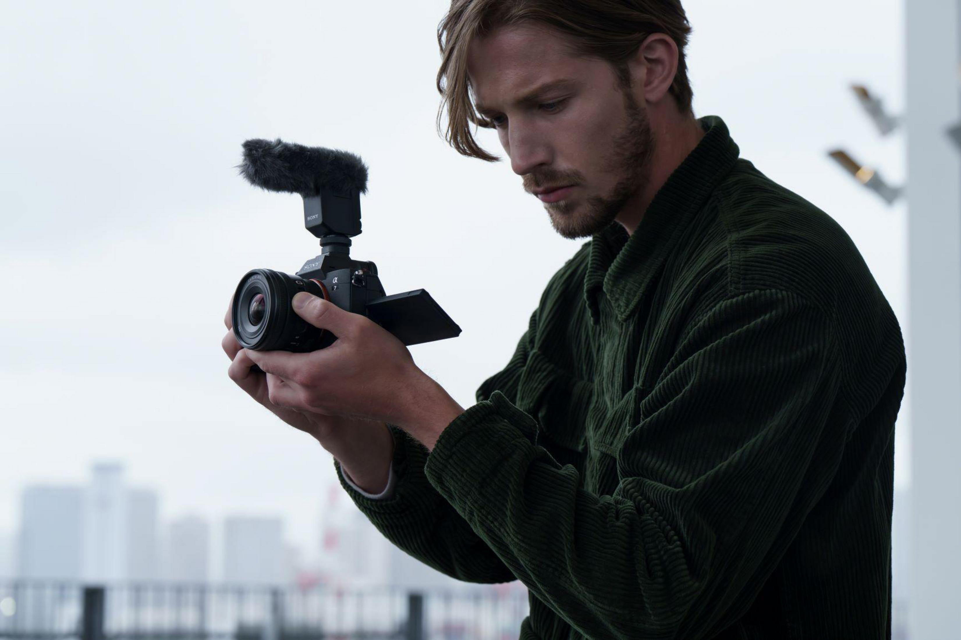 Mężczyzna trzymający aparat. Mężczyzna z brodą trzyma aparat z dołączonym mikrofonem.