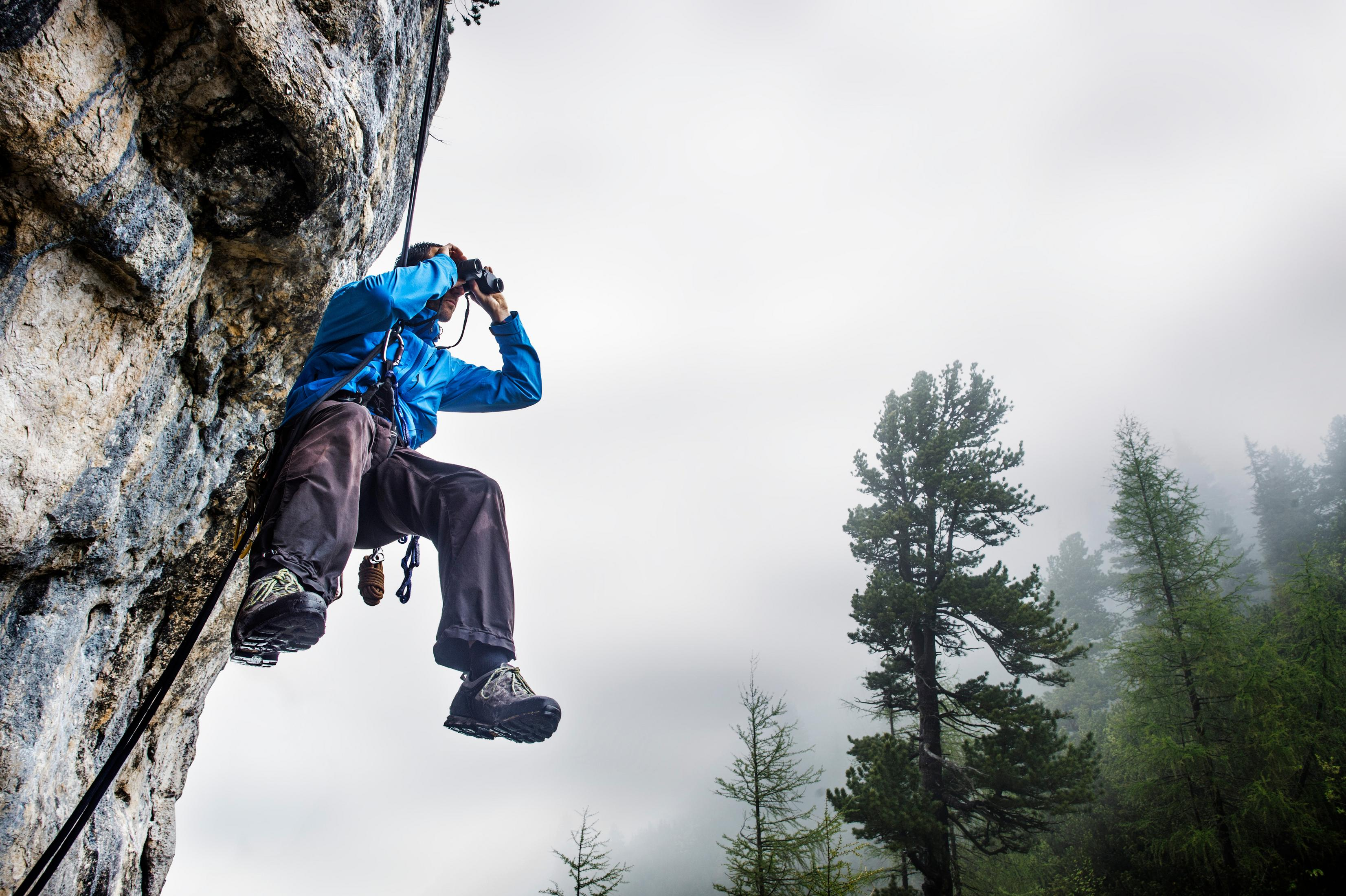 Osoba trzymająca butelkę wody. Tło to jasnoniebieskie niebo i zielone drzewa.