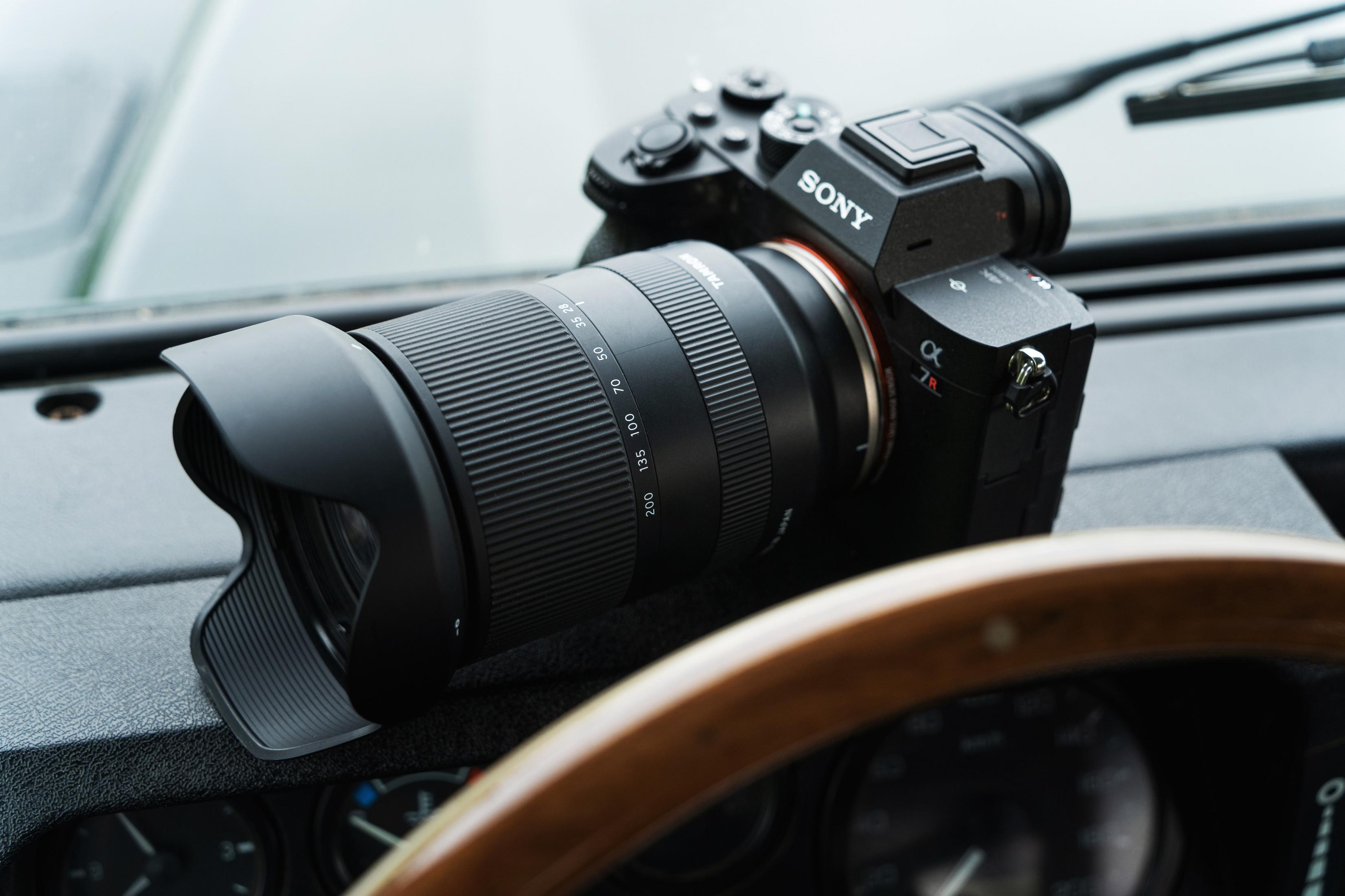 Aparat i obiektyw na desce rozdzielczej samochodu, z aparatem Sony i obiektywem Tamron.