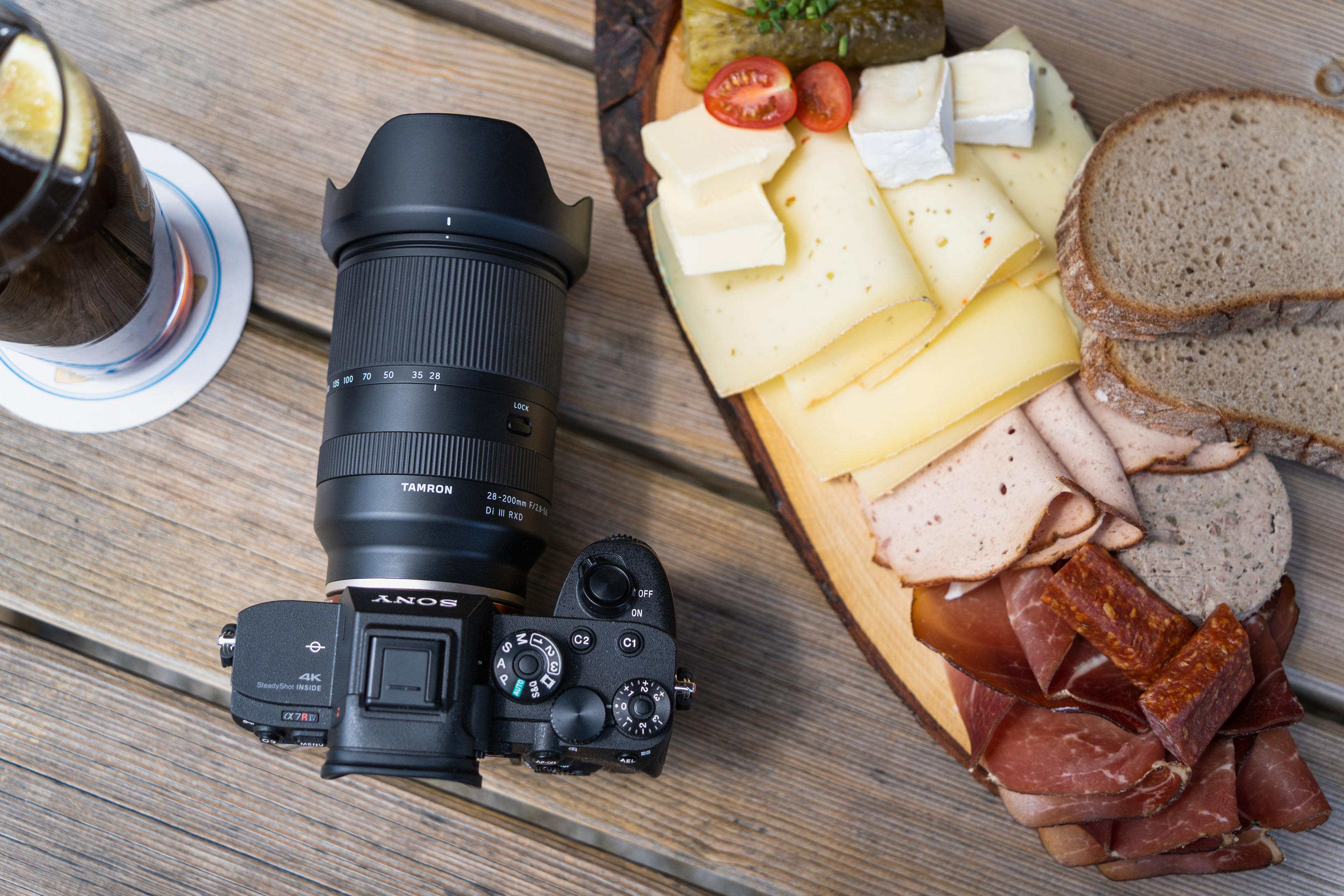 Aparat z obiektywem na drewnianym stole z jedzeniem i piciem.