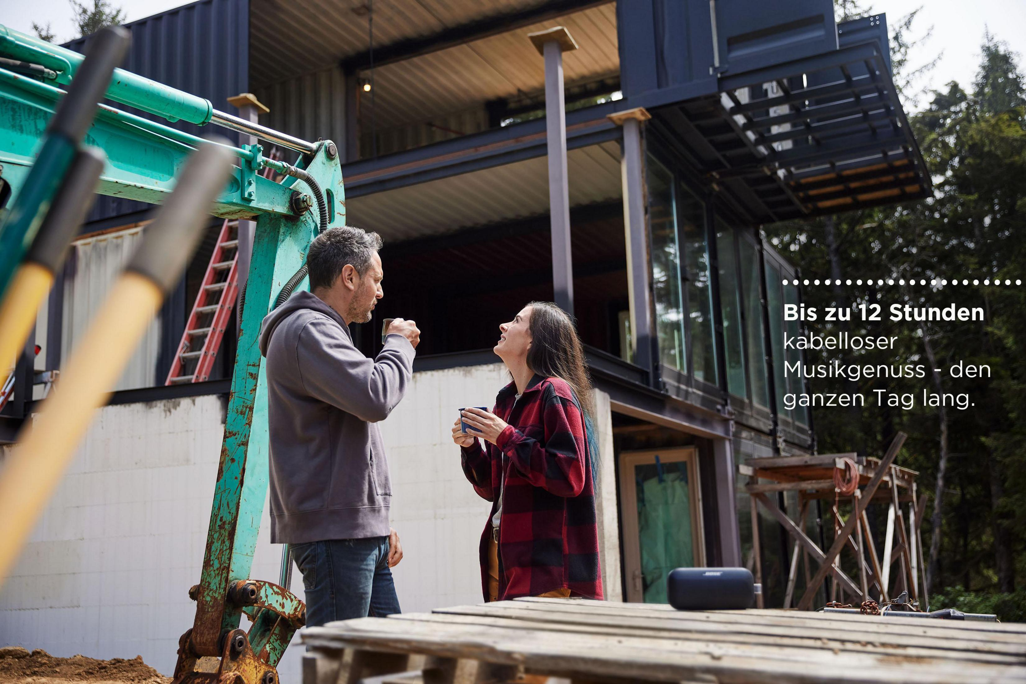 Dos personas hablando cerca de una obra con excavadora y casa moderna.