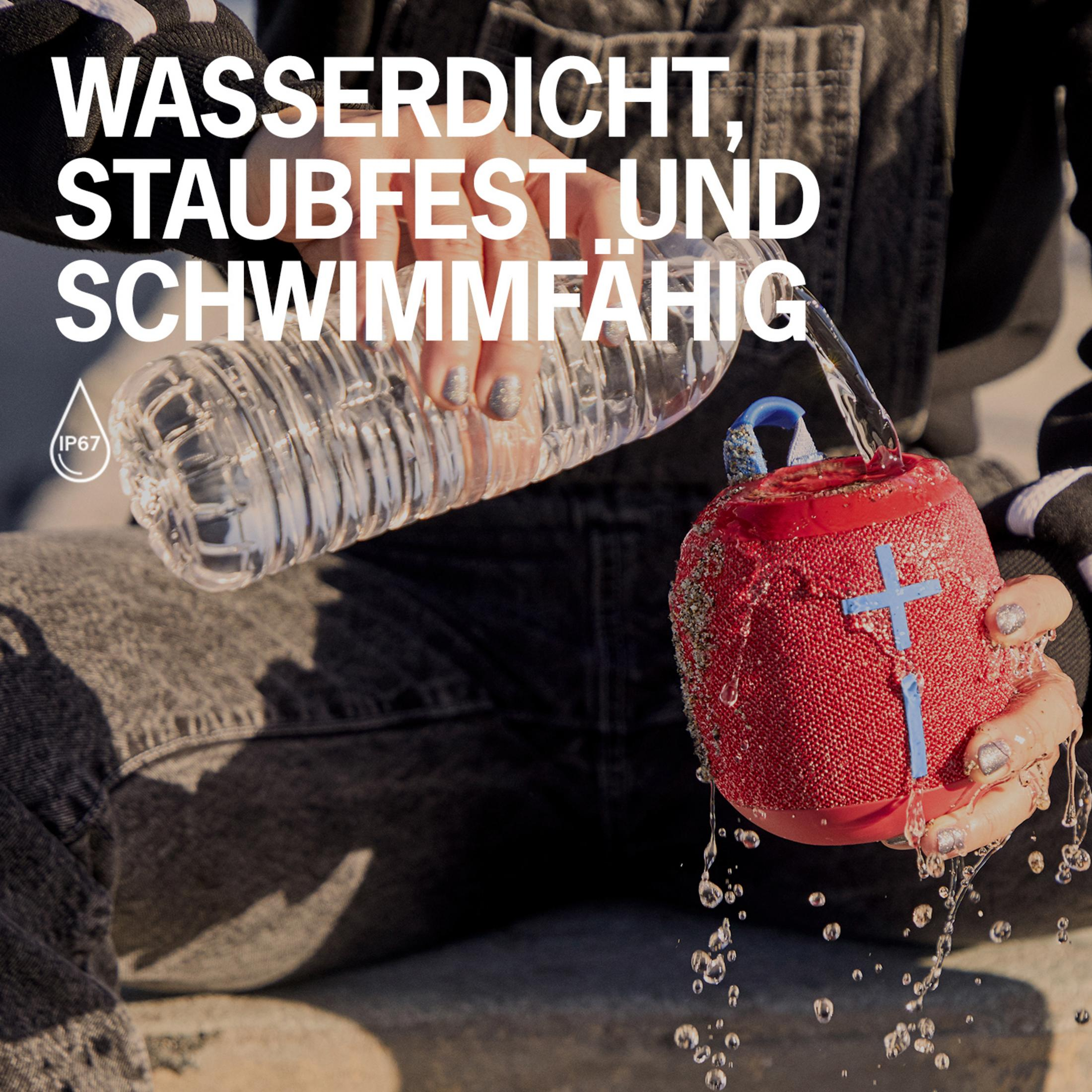 Osoba wylewa wodę na czerwony głośnik. Tekst mówi: wodoodporny, pyłoszczelny i pływający.