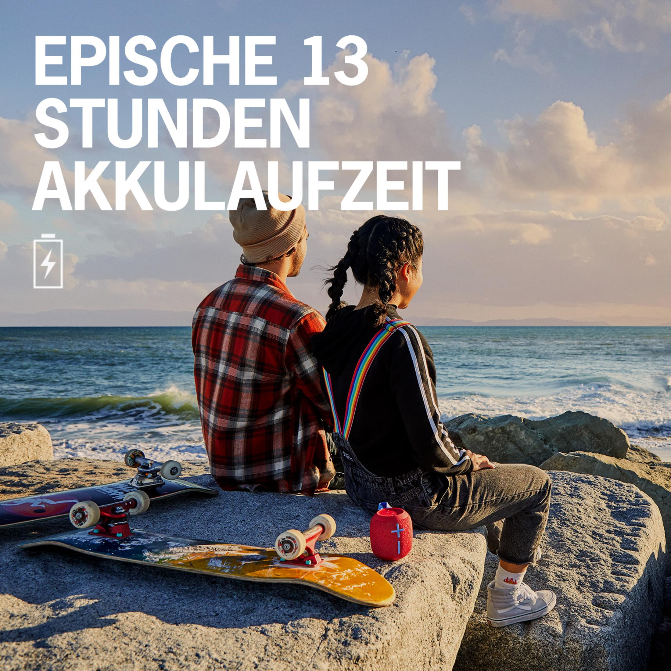 Dwie osoby siedzące na skałach nad oceanem. Tekst: EPISCHE 13 STUNDEN AKKULAUFZEIT (Epicka żywotność baterii 13 godzin).