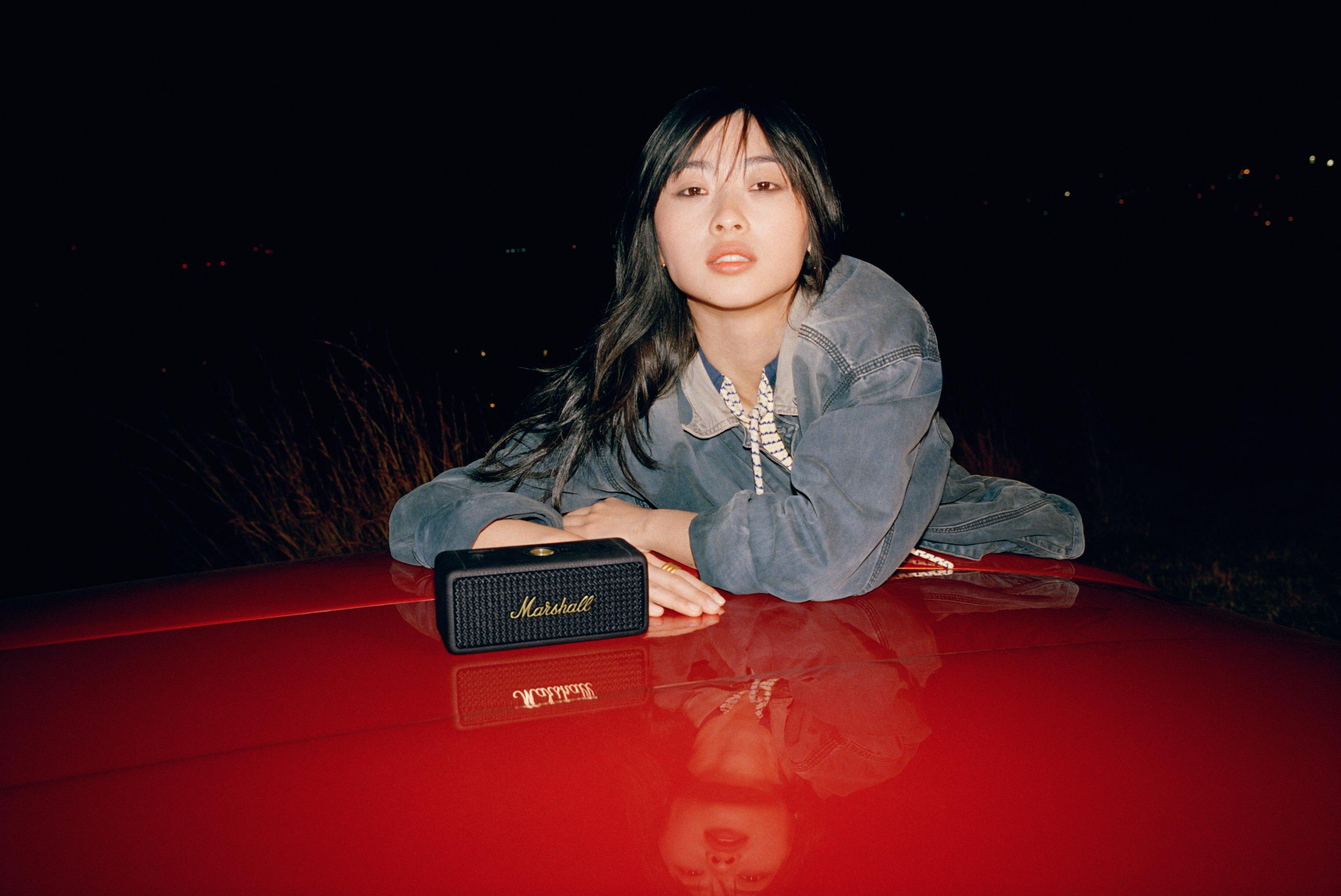 Mujer en capó rojo, altavoz negro, escena nocturna.