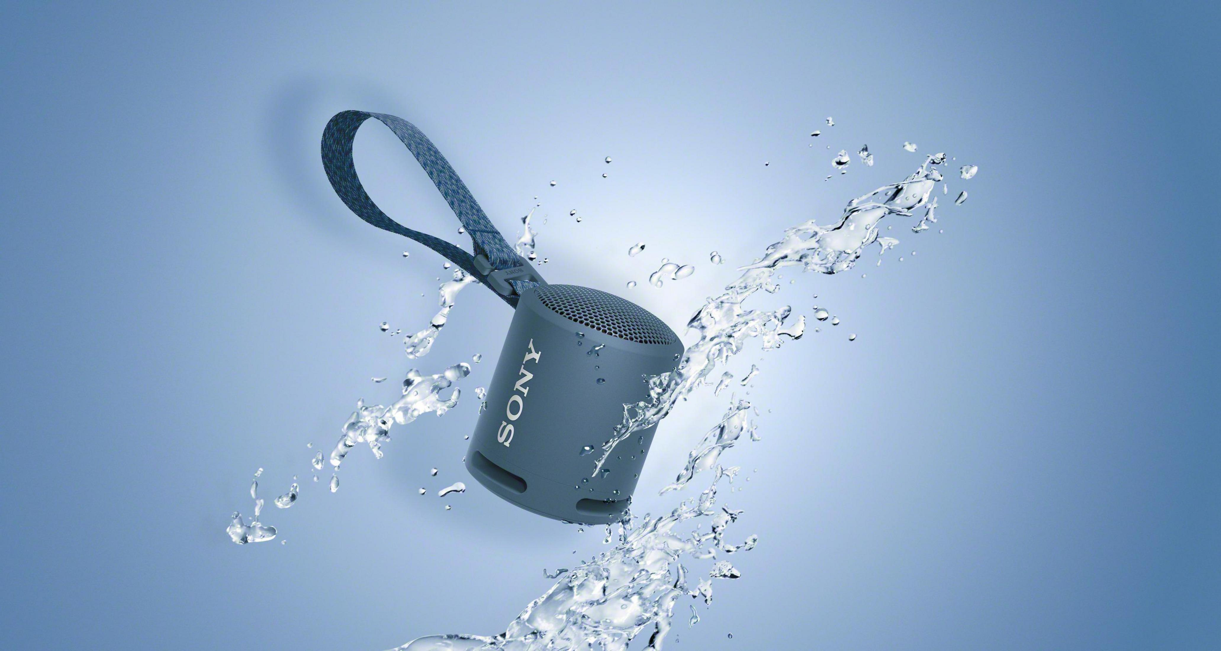 Altoparlante Sony grigio con cinturino blu, circondato da schizzi d'acqua.