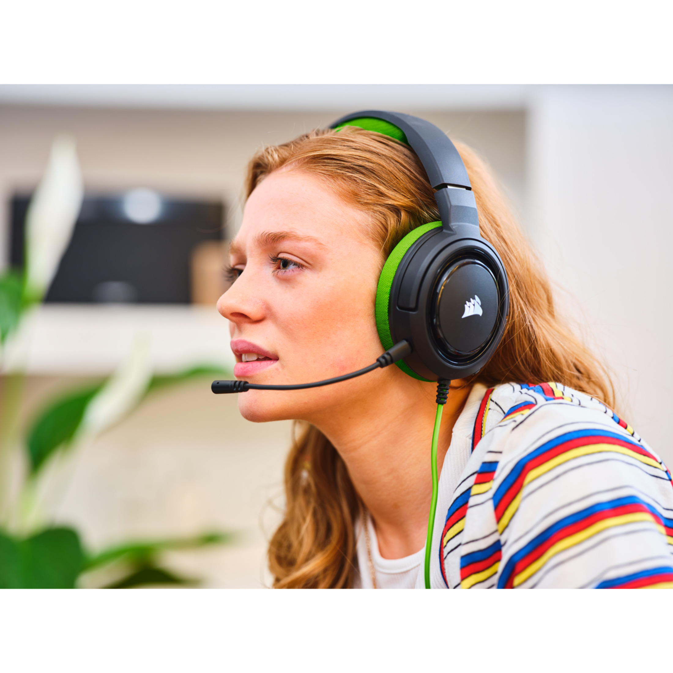 Kobieta w zestawie słuchawkowym dla graczy, patrząca w prawo. Zestaw jest czarny i zielony.