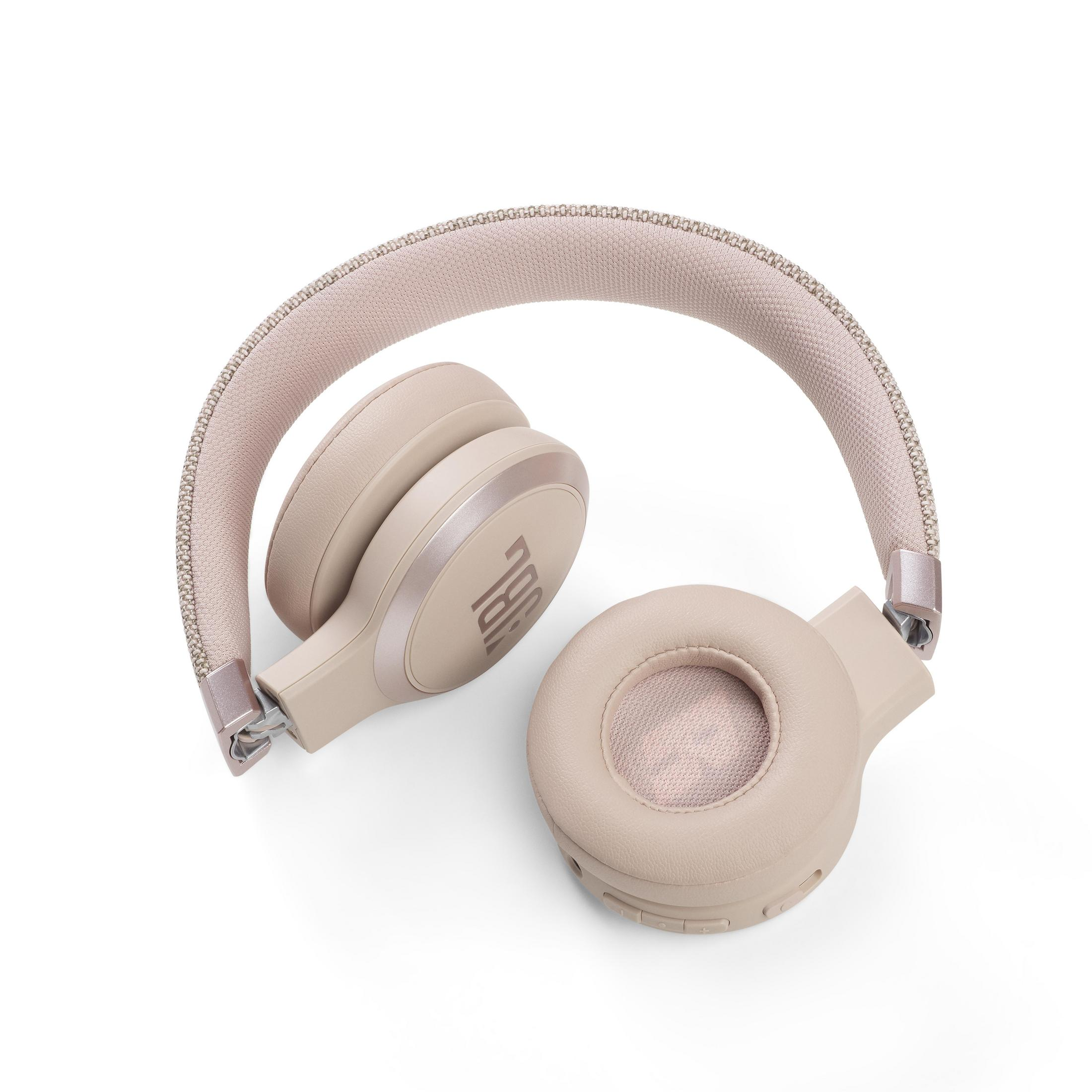 Auriculares JBL rosas plegados sobre una superficie blanca, vista cenital.