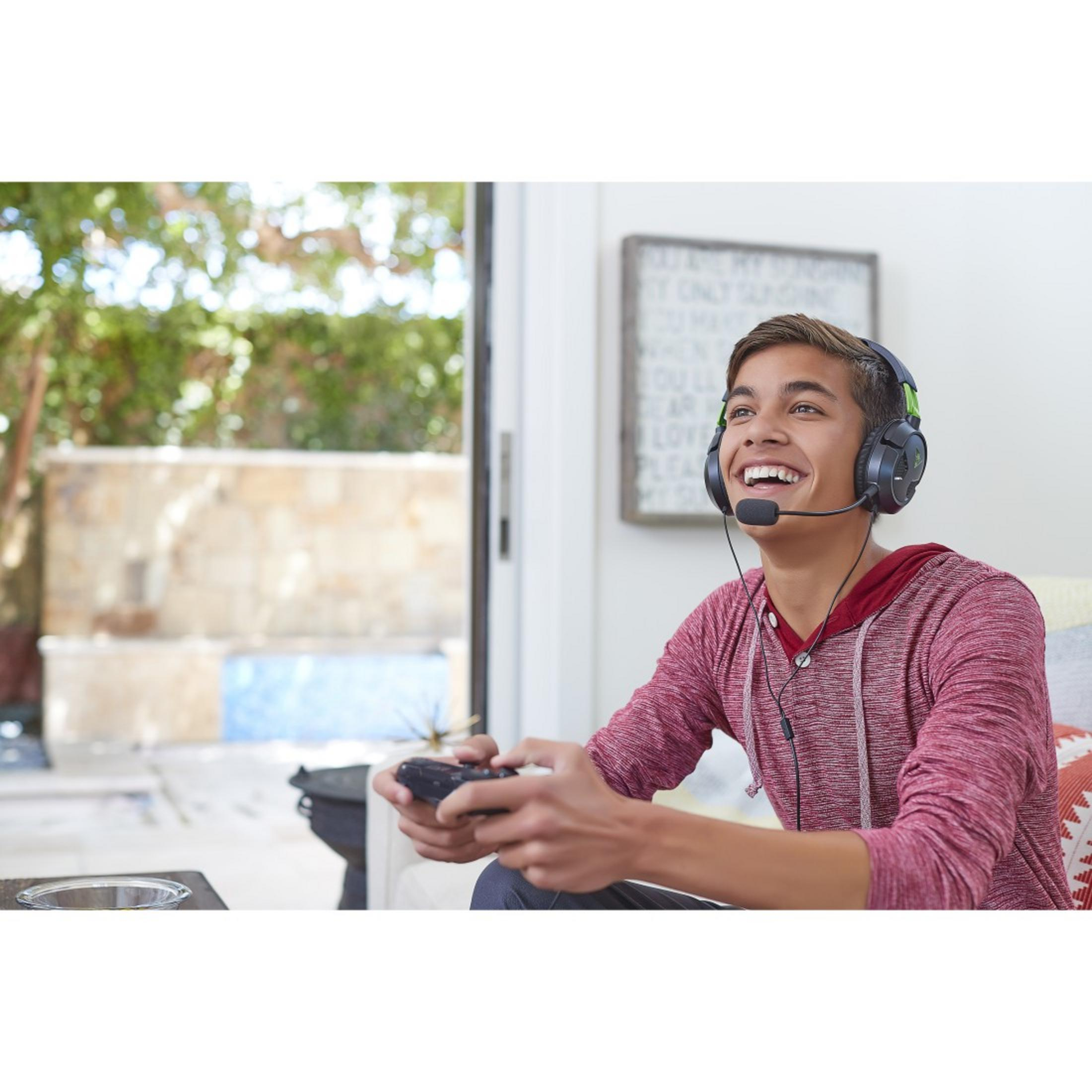 Nastolatek w słuchawkach gra w grę z kontrolerem, uśmiechając się.