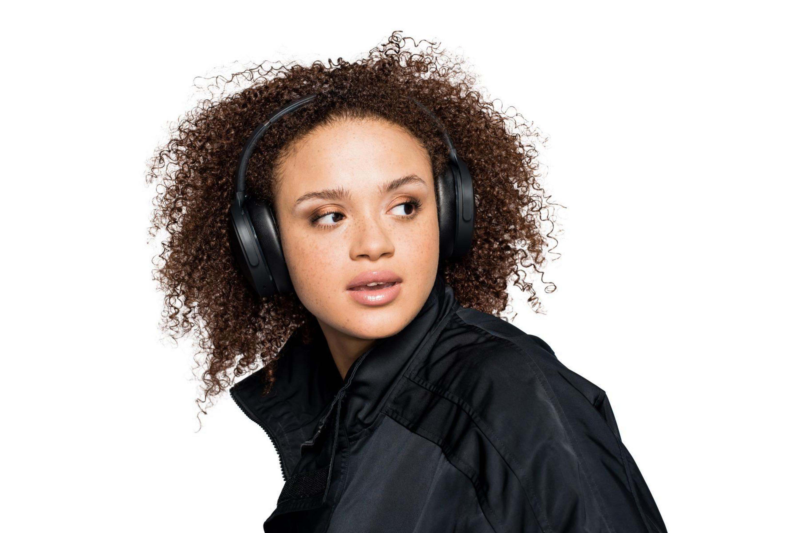 Kobieta w czarnych słuchawkach, spoglądająca przez ramię.