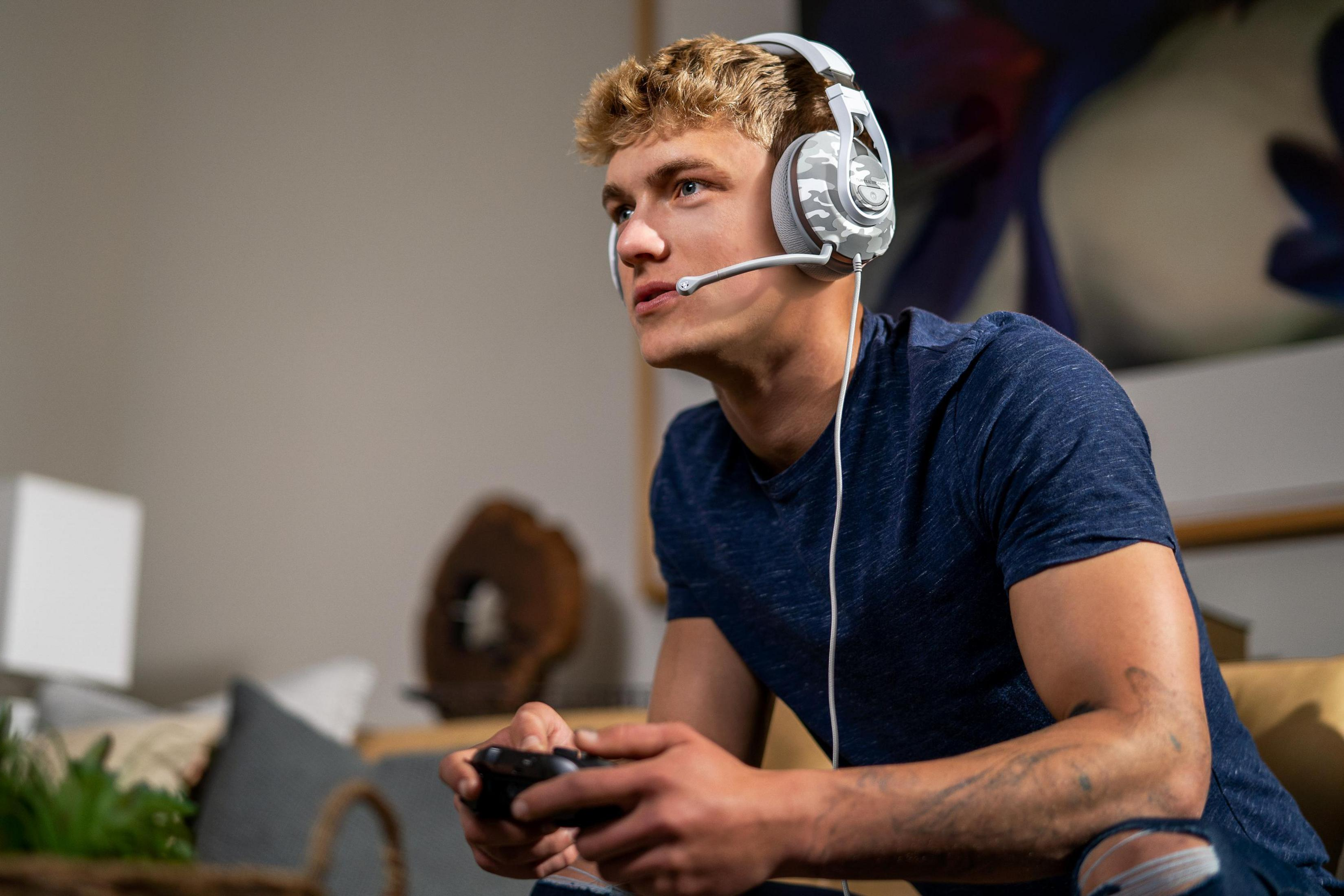 Un giovane che indossa delle cuffie da gioco sta giocando. Tiene in mano un controller.