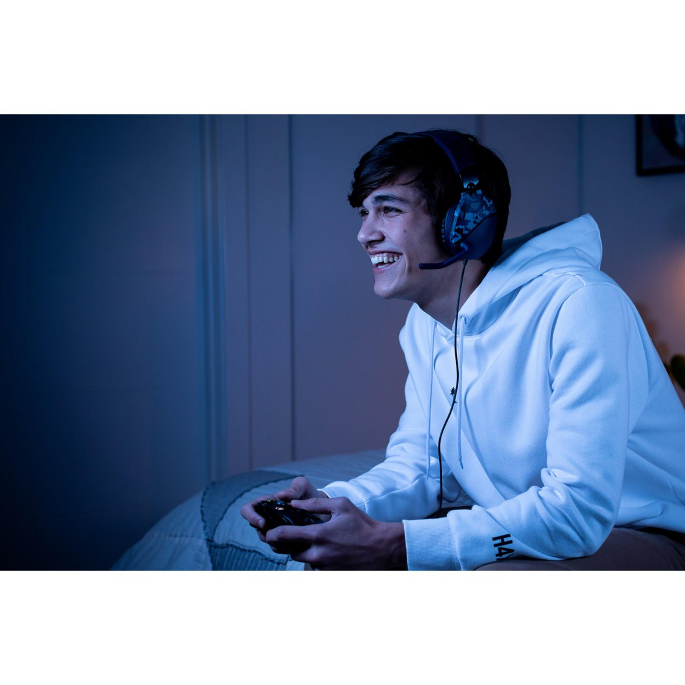 Mężczyzna uśmiechnięty podczas gry z kontrolerem, w zestawie słuchawkowym.