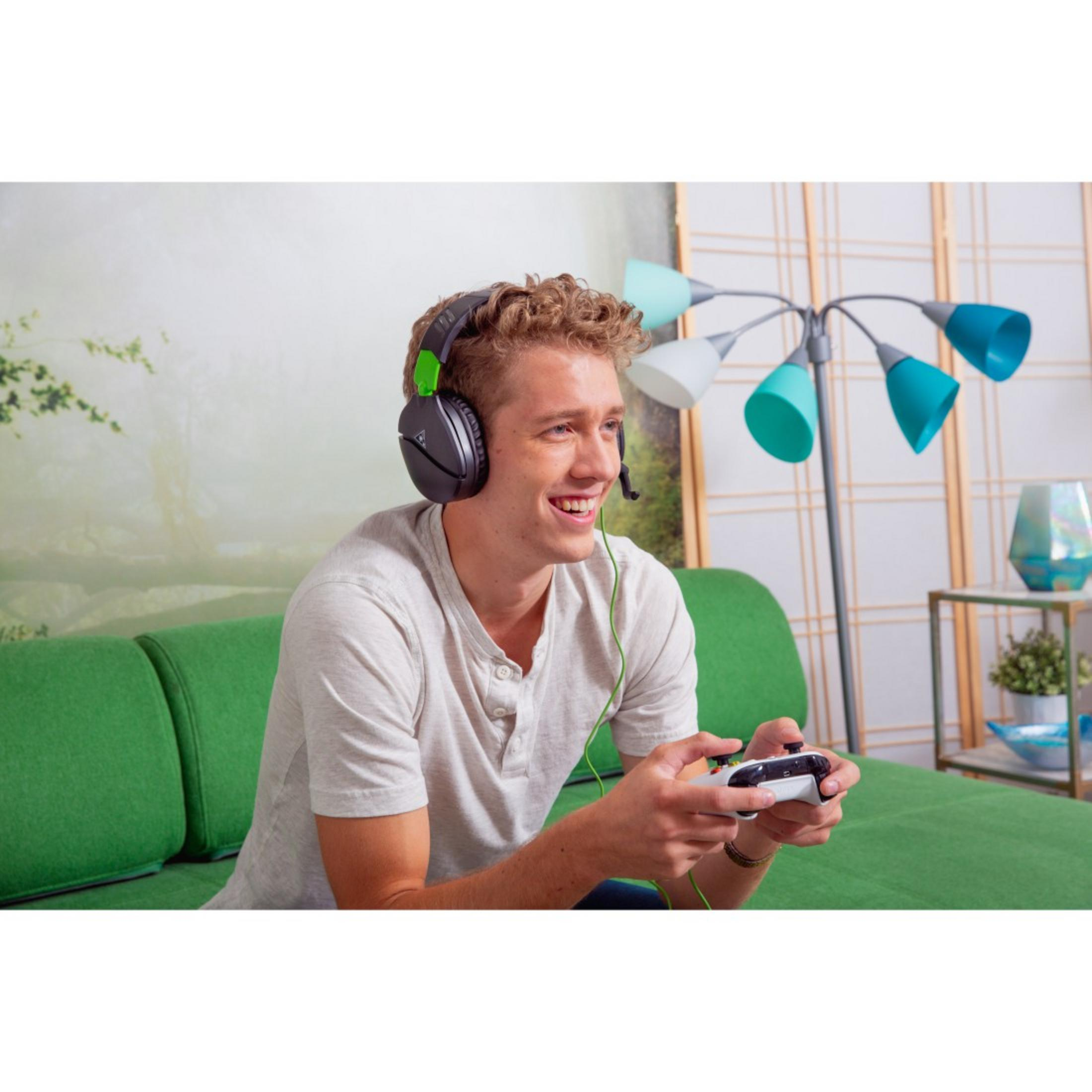 Junger Mann spielt Videospiel mit Kopfhörern und Controller.
