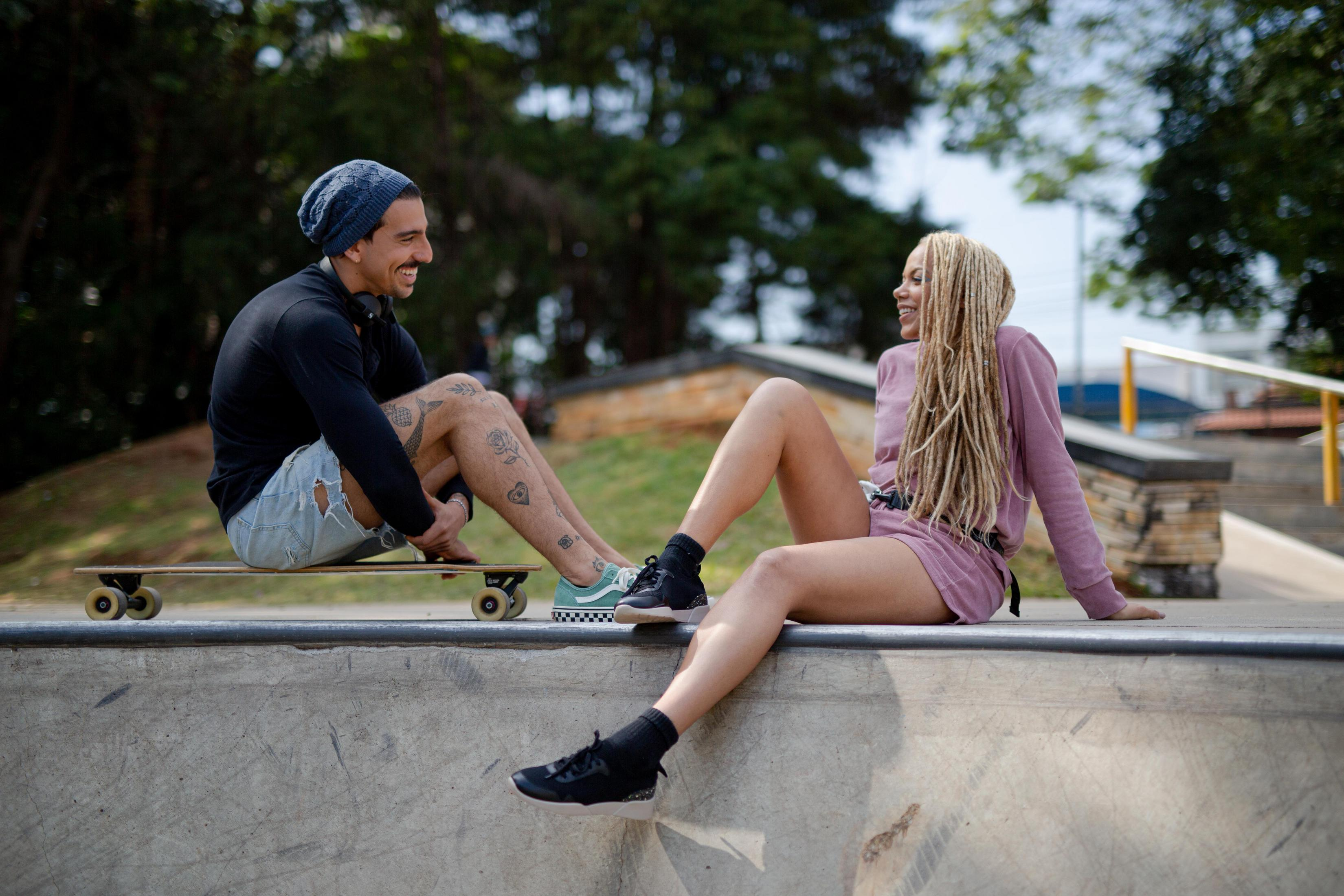 Un couple est assis sur une rampe de skateboard, souriant et riant.